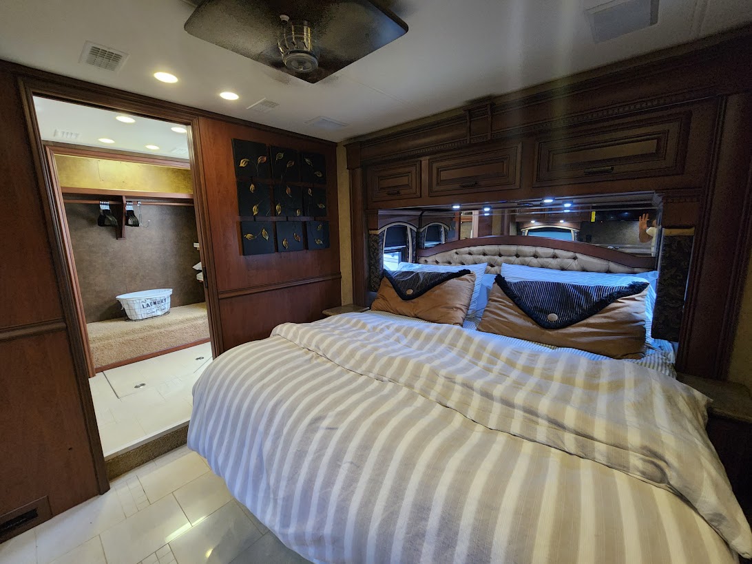 Spacious RV rental bedroom with a large bed, built-in storage, and a walk-in laundry closet.. Entegra Coach Aspire 2013