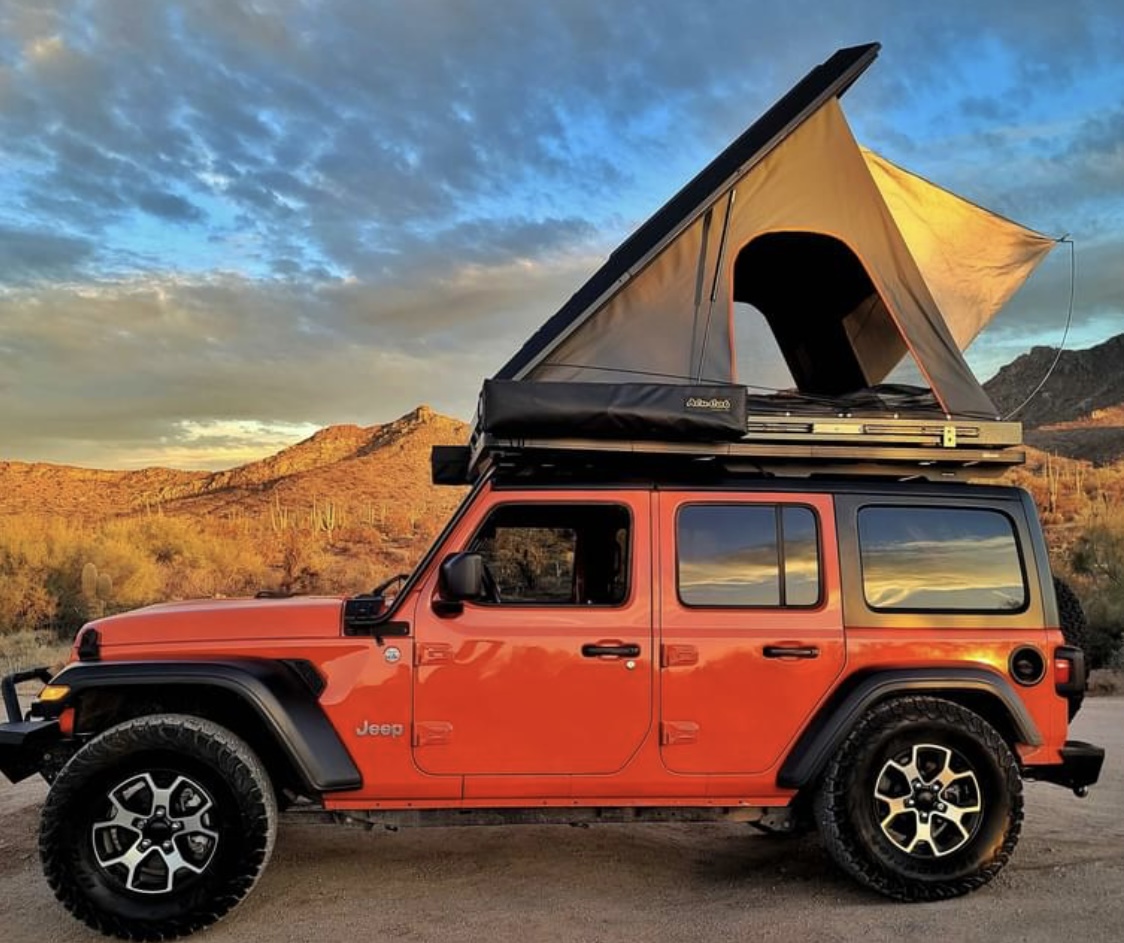 Overland adventure: Orange Jeep with rooftop tent in desert sunset. Consider this unique RV rental for your next camping trip.. Jeep Wrangler 2018
