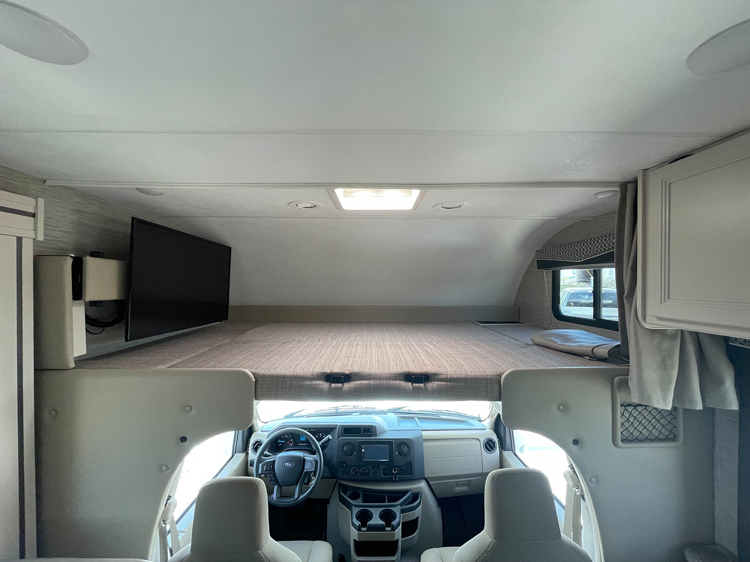 View inside an RV rental: over-cab bunk with TV, above the driver's cockpit.. Thor Chateau 2022
