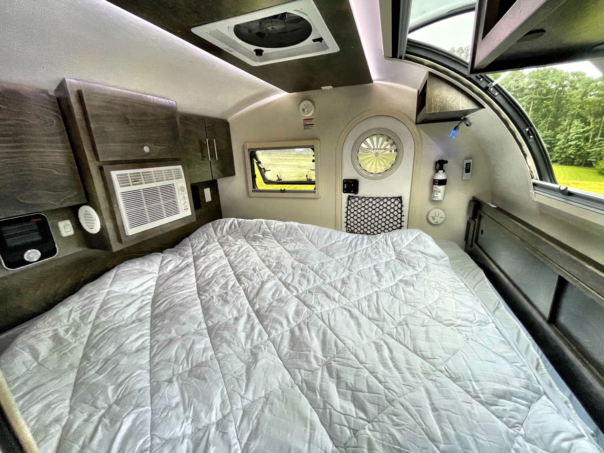 Bright, compact rv rental interior featuring a large bed, AC unit, and scenic windows for comfortable travels.. nuCamp T@G 2021
