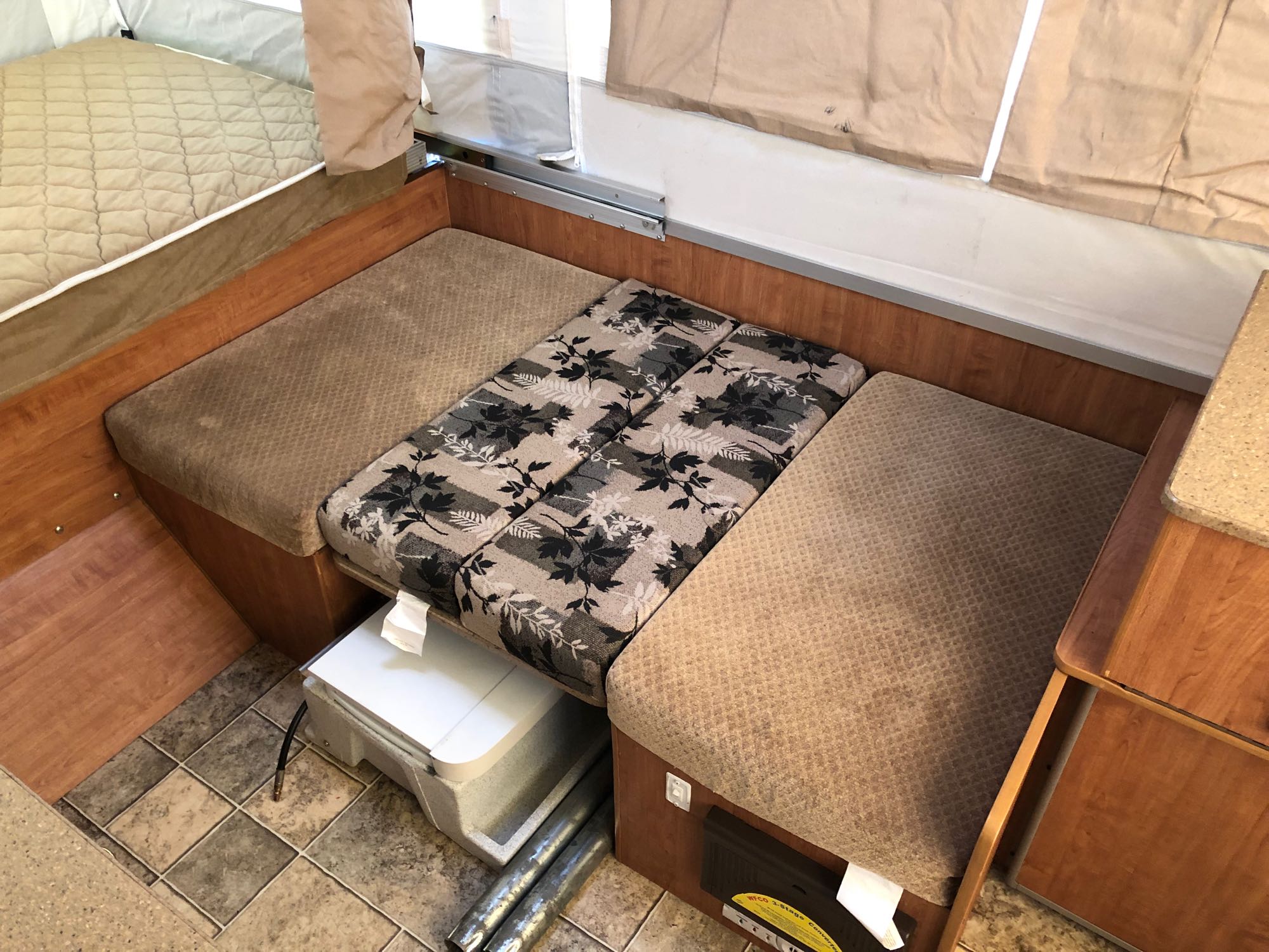Pop-up RV rental: cozy interior with convertible dinette, patterned cushions, and bed area. Wood trim and canvas walls.. Forest River Rockwood LTD 2010