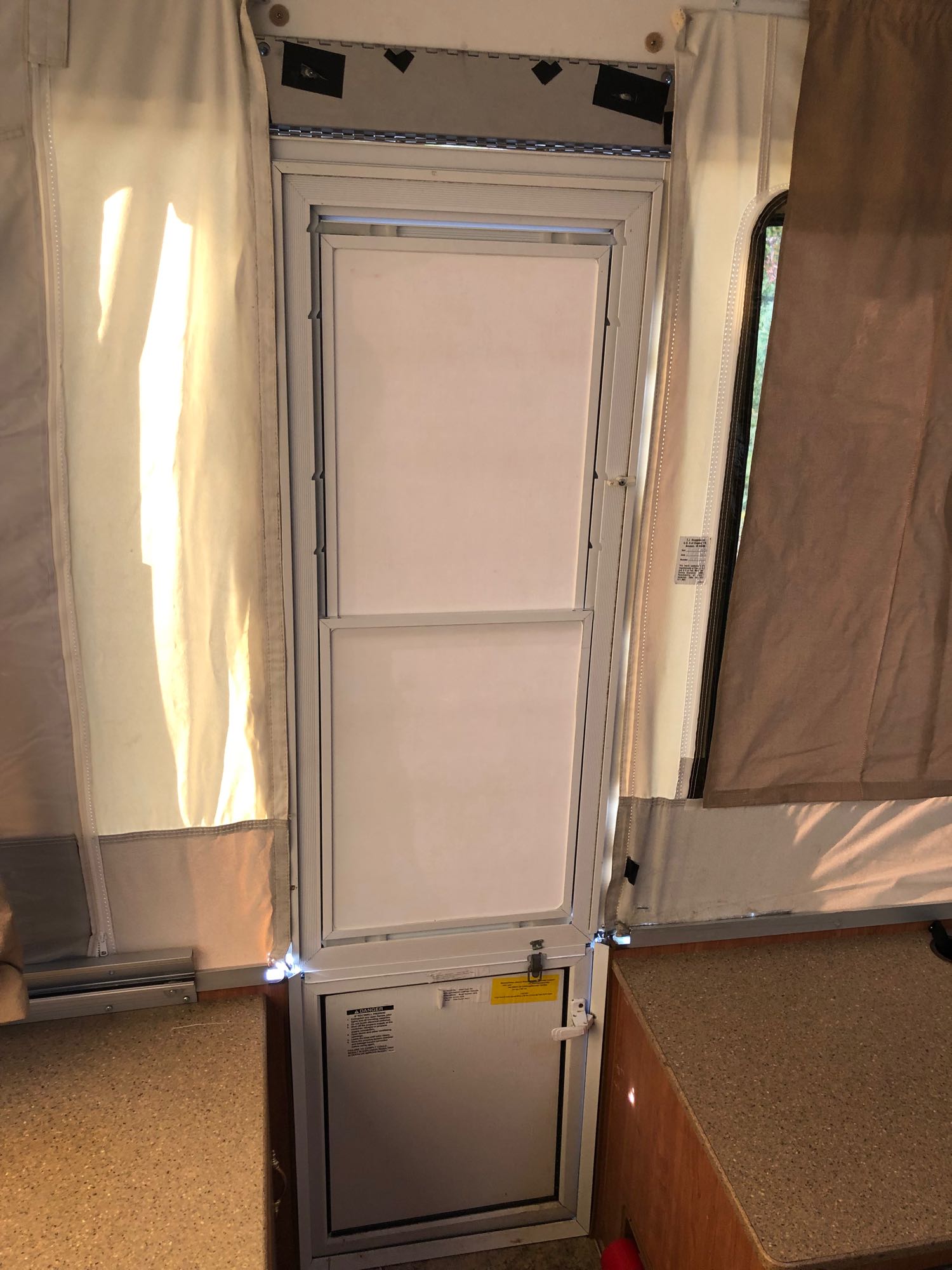 Interior of an RV rental pop-up camper, showing the entry door, canvas walls, and counter space.. Forest River Rockwood LTD 2010