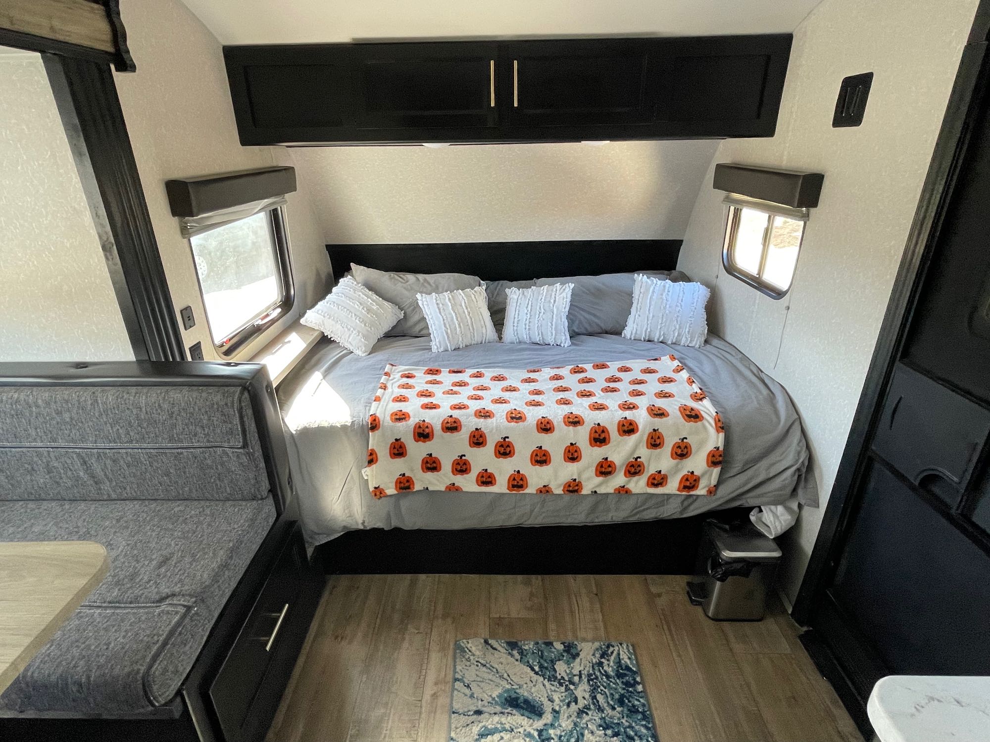 Cozy RV rental bedroom: comfy bed with a pumpkin blanket, dinette, and bright windows for your next adventure.. Forest River 17bh 2022