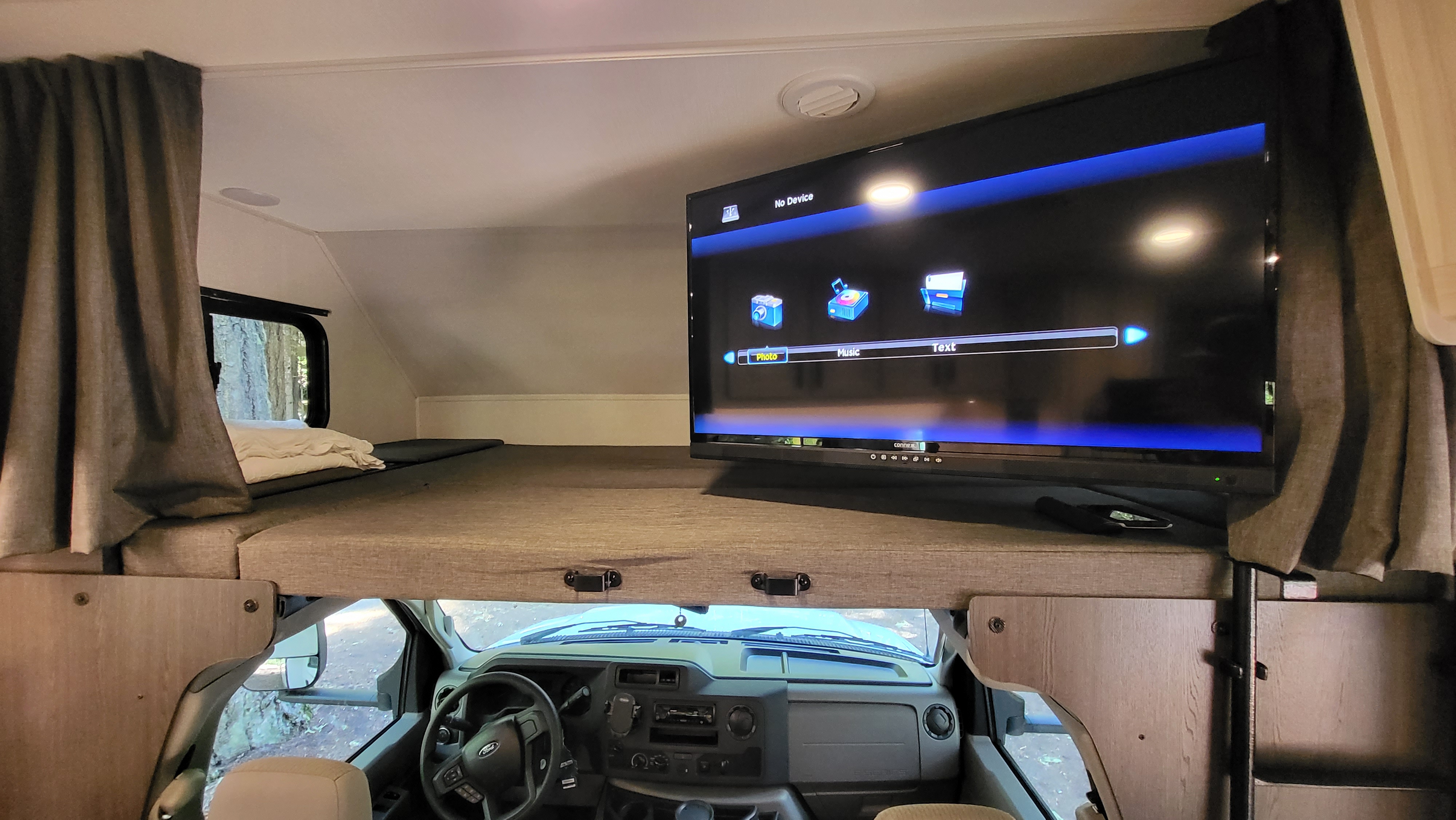 RV rental interior: A TV sits on the cab-over bunk above the driver's area, offering entertainment in this cozy travel space.. Forest River Sunseeker LE 2022