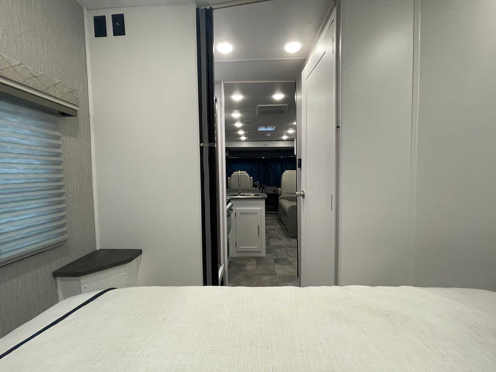 Spacious RV rental interior from the bedroom, looking into the kitchen and living area. Modern design, ideal for travel.. Coachmen Pursuit 2023