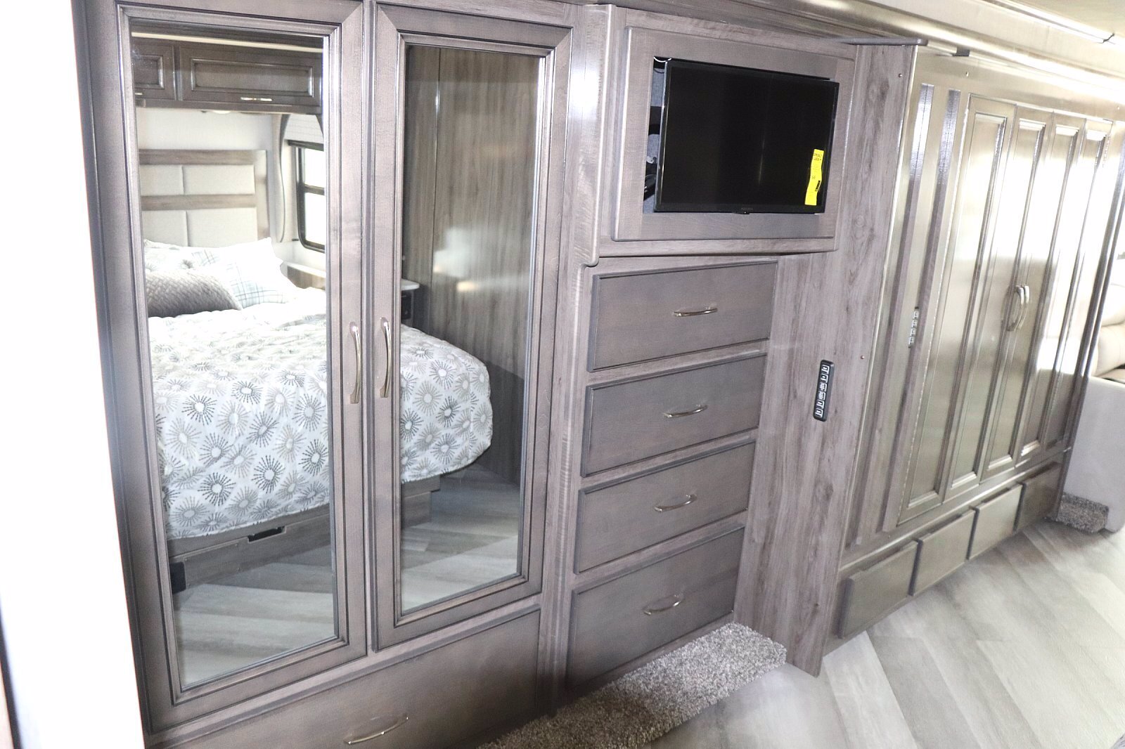 Stylish RV rental interior: bedroom view with mirrored closet, TV, and built-in storage drawers.. Fleetwood Bounder 2024