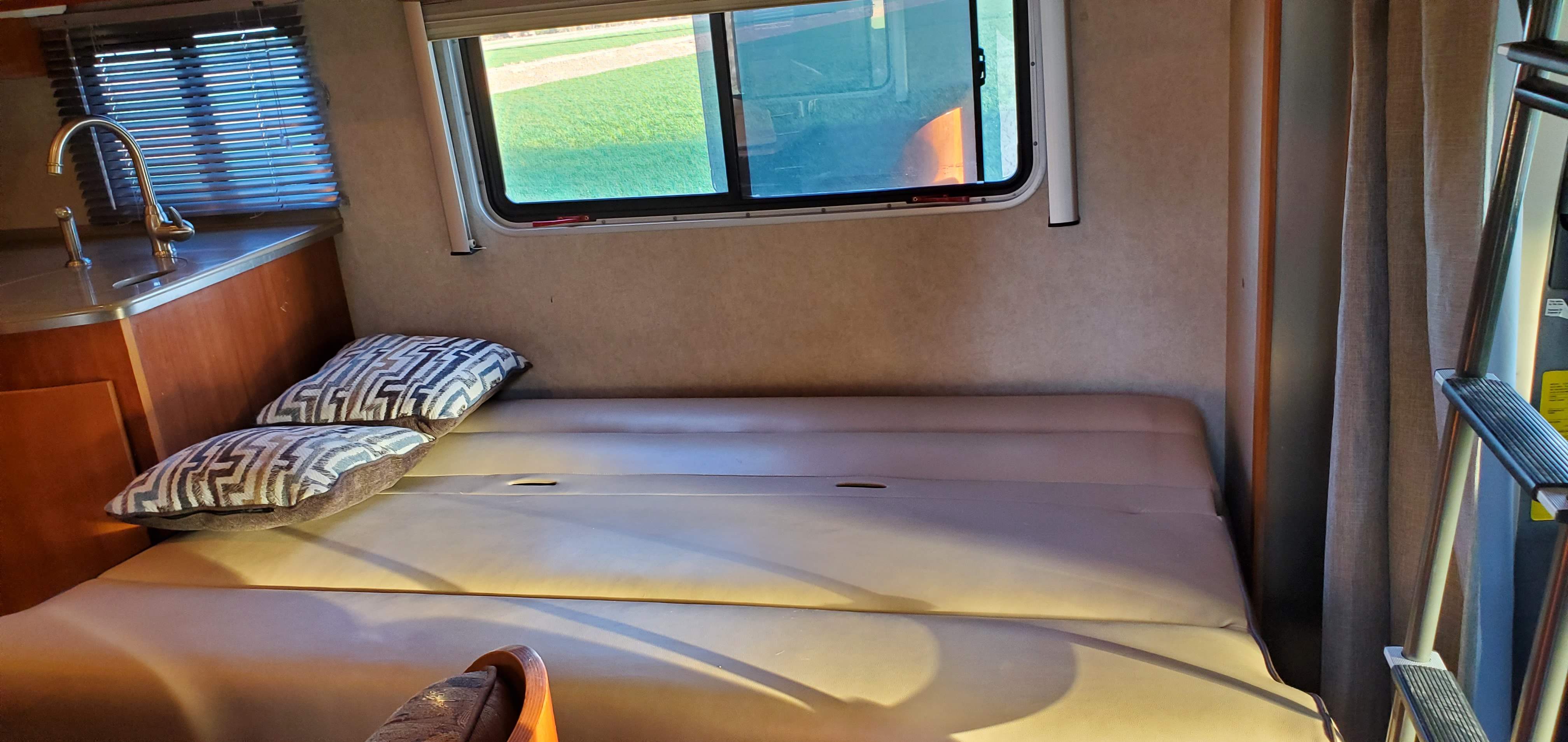 Cozy RV rental interior with a kitchen sink, window, and versatile seating that converts to a bed, plus a bunk ladder.. Fleetwood Sprinter 2008