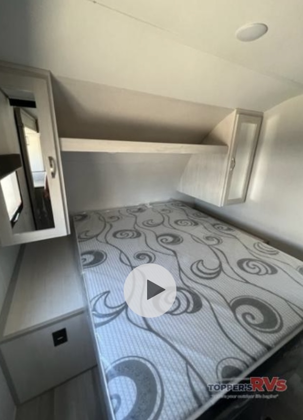 RV rental bedroom interior: comfy bed with patterned mattress, overhead storage, and mirrored cabinet. Ready for adventure!. Prime Time Tracer 2022