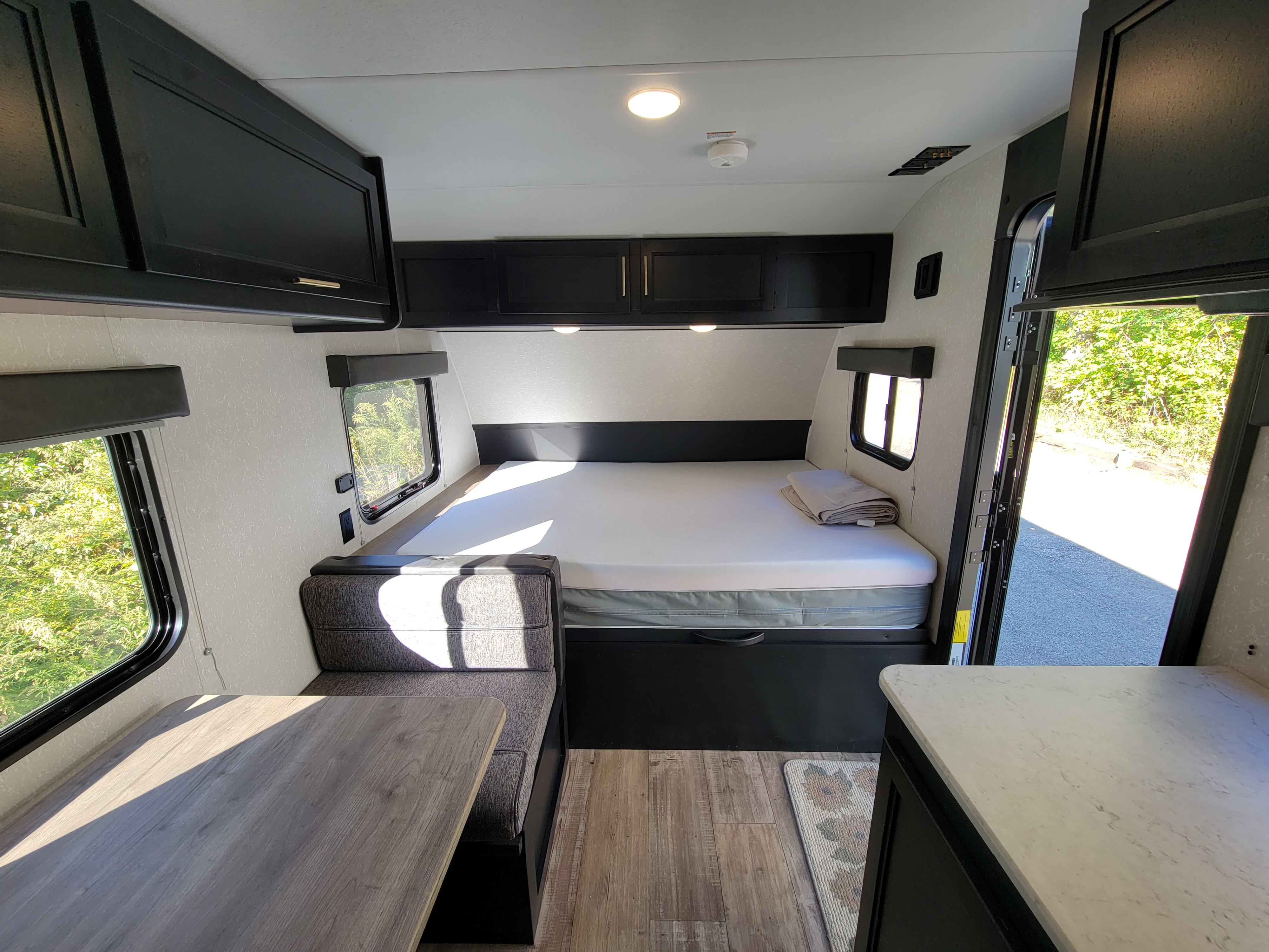Modern RV rental interior with a cozy bed, dinette with table, and compact kitchen space, perfect for travel.. Forest River Cherokee Wolf Pup 2021