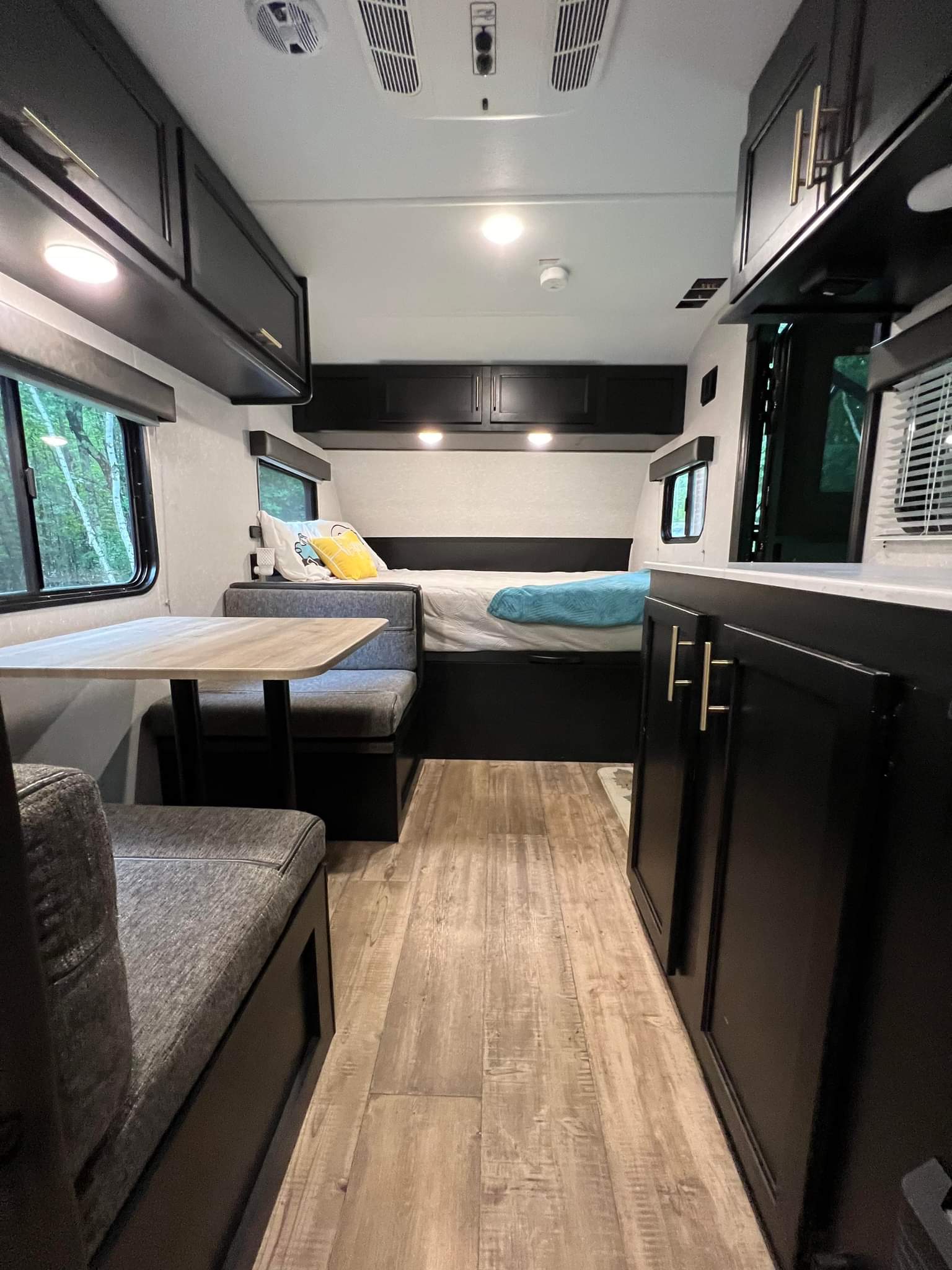 View inside an RV rental showing its compact dining area, bed, and sleek black cabinets. Ideal for travel.. Forest River Cherokee Wolf Pup 2021