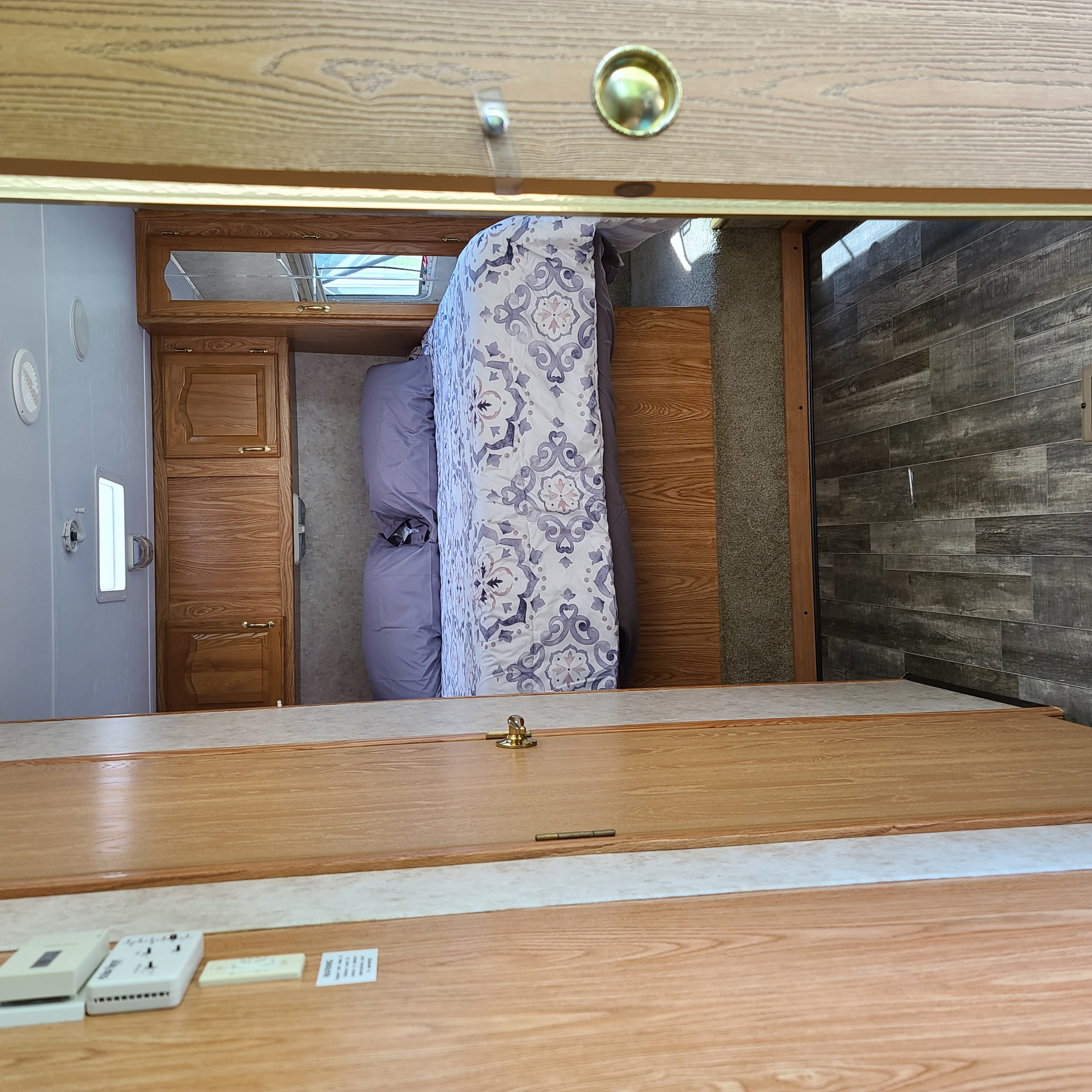 Experience comfort in this RV rental bedroom: patterned bedding, wood cabinetry, and varied flooring. A cozy interior.. Cedar Creek Cedar Creek Fifth Wheel 2005