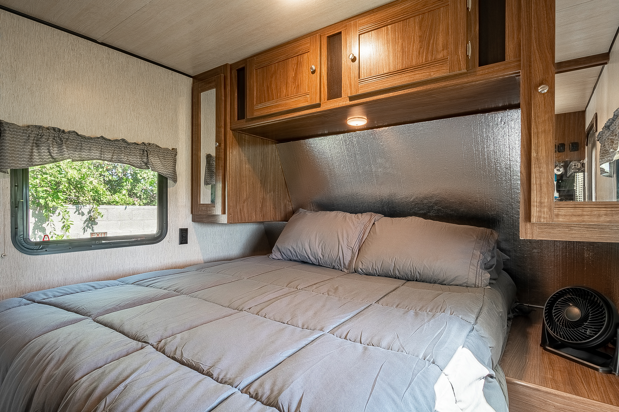Well-appointed RV rental bedroom with a comfortable bed, wooden cabinets, and a window for bright travel mornings.. Heartland RVs Pioneer 2018
