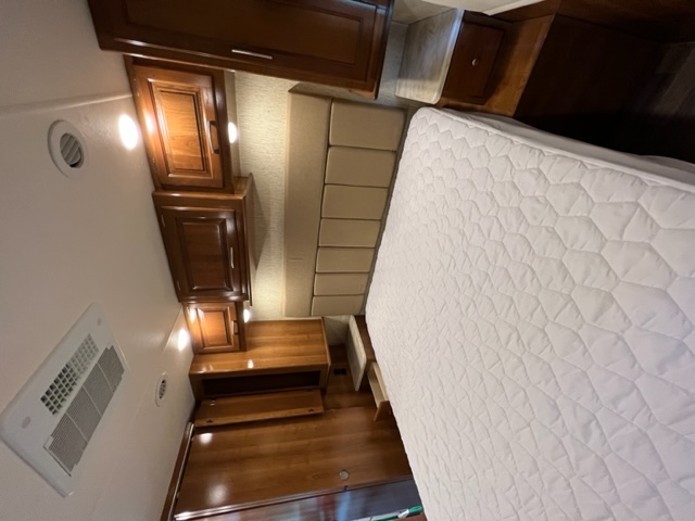 Comfortable RV rental bedroom featuring a white bed, wood cabinets, and air conditioning for your travels.. Coachman Mirada 2018