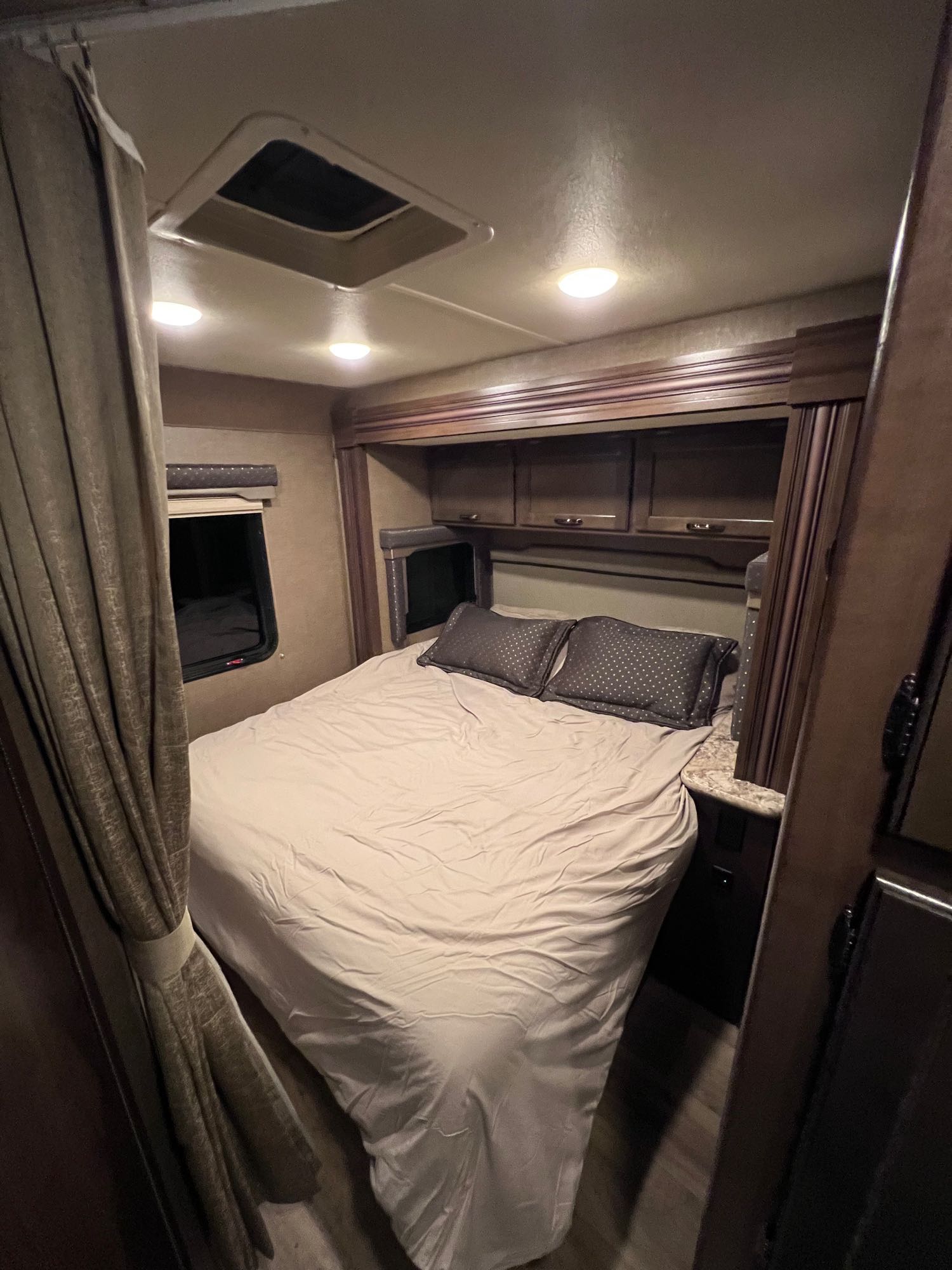 Cozy RV rental bedroom interior with a bed, overhead cabinets, and ceiling vent. Ready for your adventure.. Thor Freedom Elite 2018