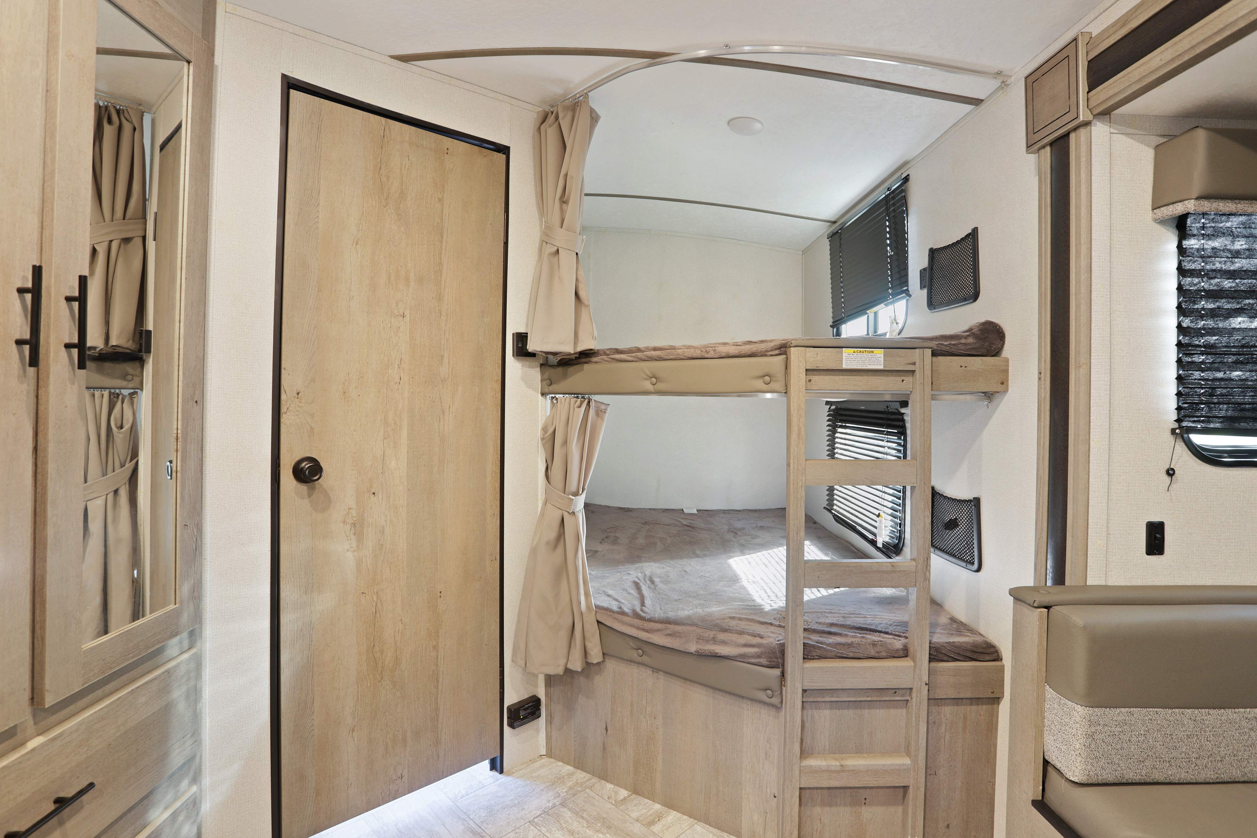 Cozy RV rental interior featuring comfortable bunk beds with privacy curtains and a dinette, ideal for family travel.. Keystone RV Springdale 2021