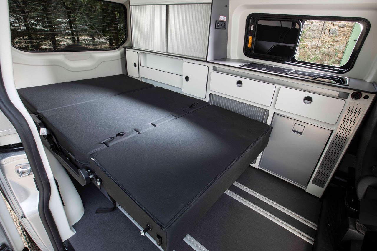 Interior of an RV rental: a laid-out bed, compact kitchen with fridge & sink, and ample storage cabinets.. Panama P10+ 2024