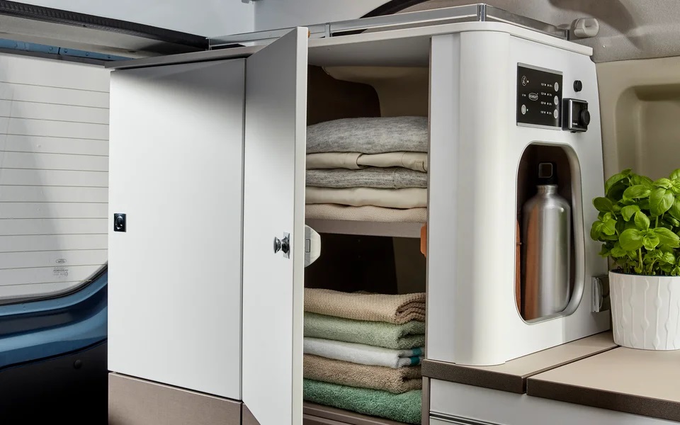RV rental interior showcasing smart storage with neatly folded clothes, towels, and a built-in water bottle holder.. Bürstner COPA 500 2023