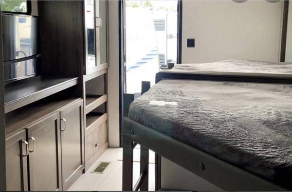The rear bedroom also features a wall-to-wall entertainment and storage system. It also has its own entrance from the rear of the camper.. Keystone RV Passport GT 2021