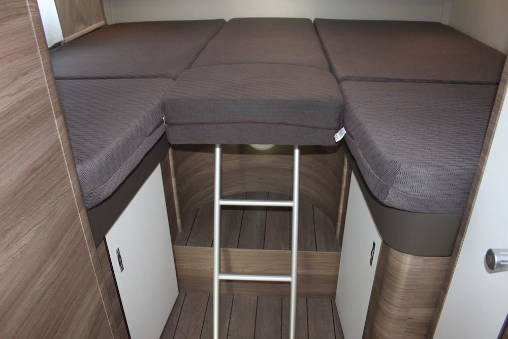 View of an RV rental's sleeping area, featuring a multi-segment bunk bed, access ladder, and lower storage.. Knaus Live Wave 700 MEG 2022