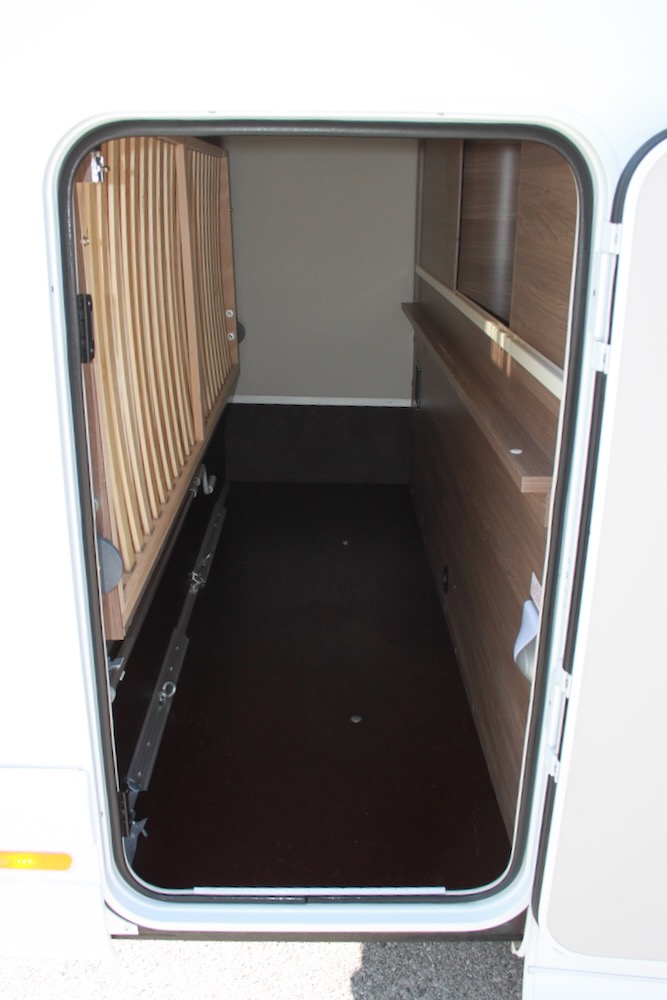 Spacious RV rental storage: view into the camper's deep garage with a lifted bed frame and shelving.. Knaus Live Wave 600 DKG 2021