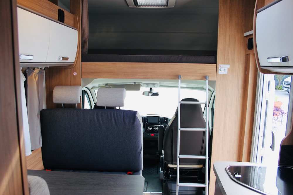 Experience comfort in this RV rental's interior, showcasing an over-cab bunk, seating, and kitchenette for travel.. Weinsberg 600 DKG 2022