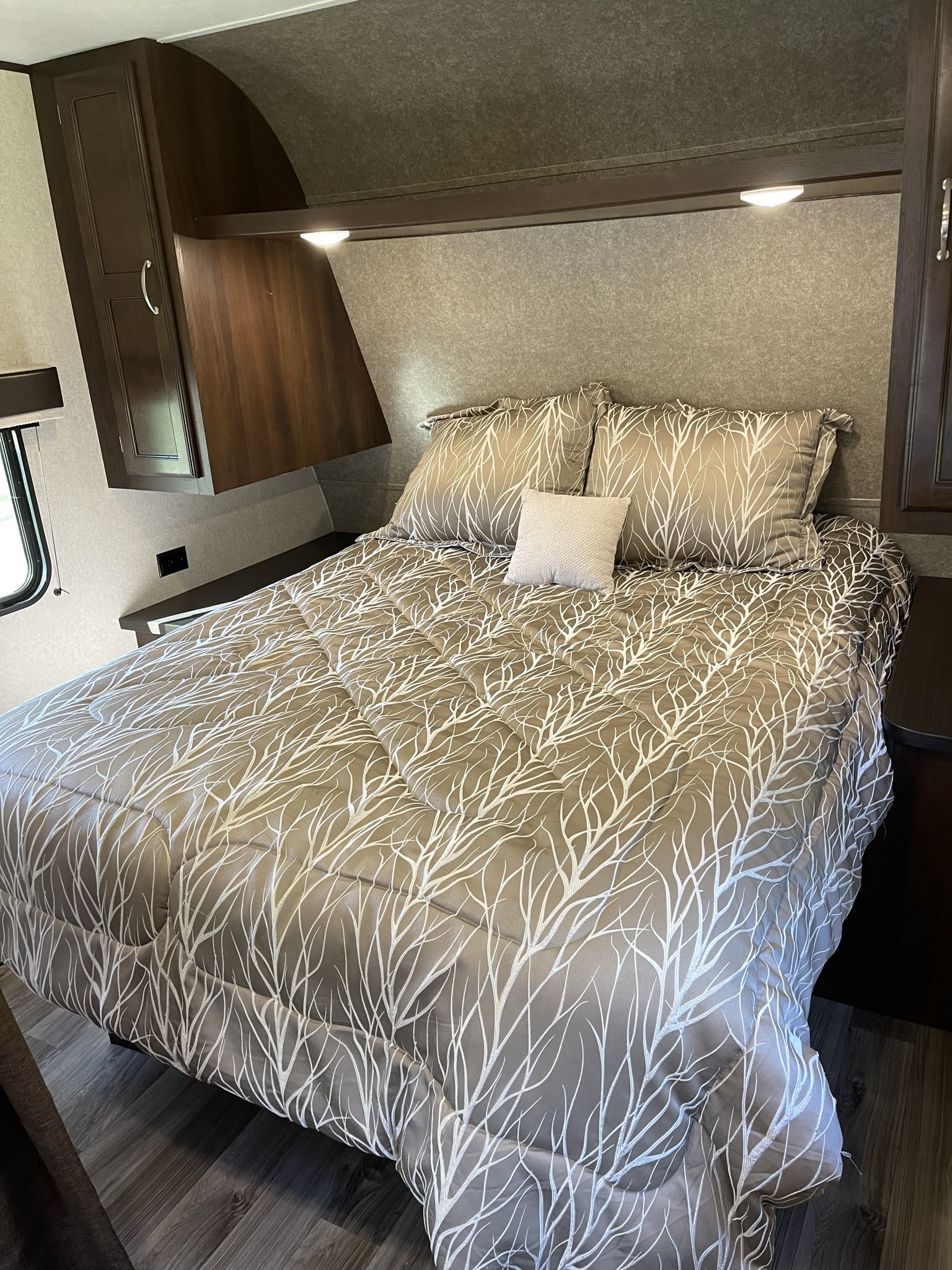 Cozy RV rental bedroom with a patterned comforter, overhead storage, and warm lighting for comfortable travel.. Jayco Jay Flight SLX Baja Edition 2018