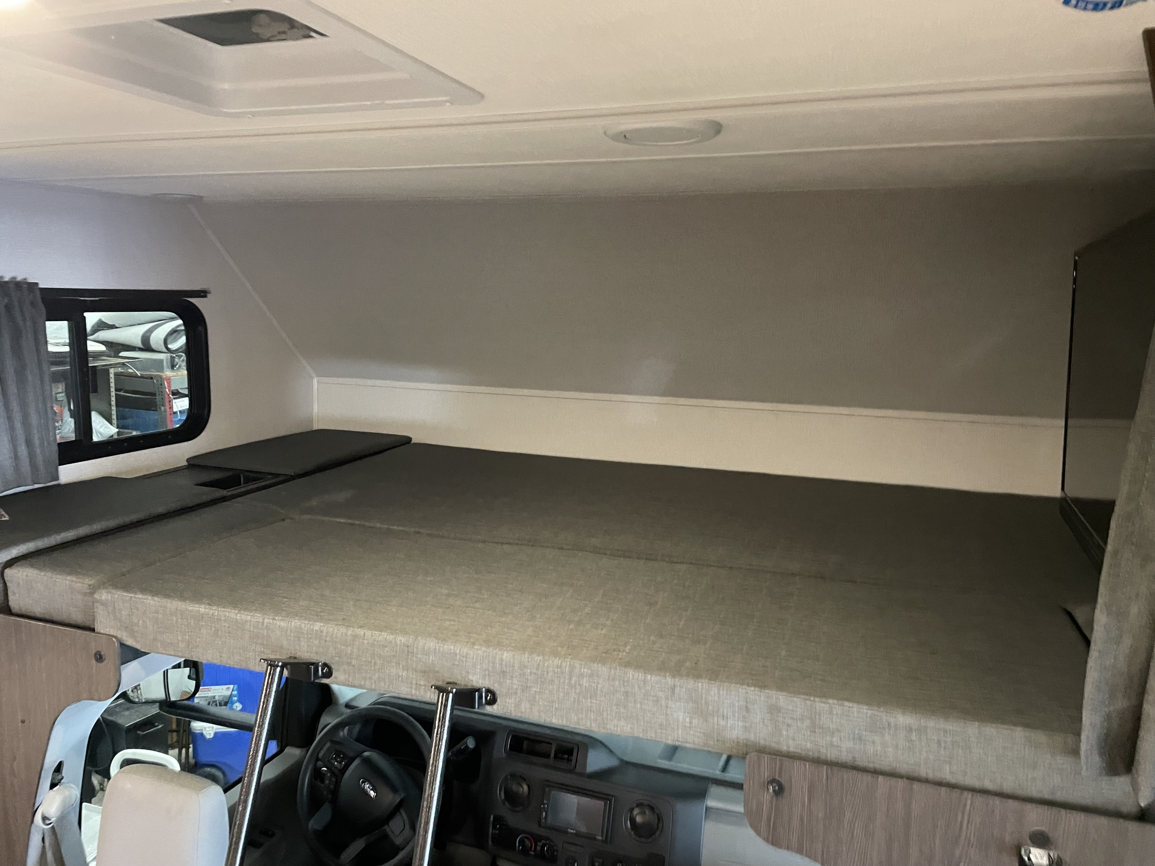 RV rental: The cozy over-cab bunk bed with mattresses, a window, and the driver's area below.. Forest River Sunseeker 2850SLE 2023