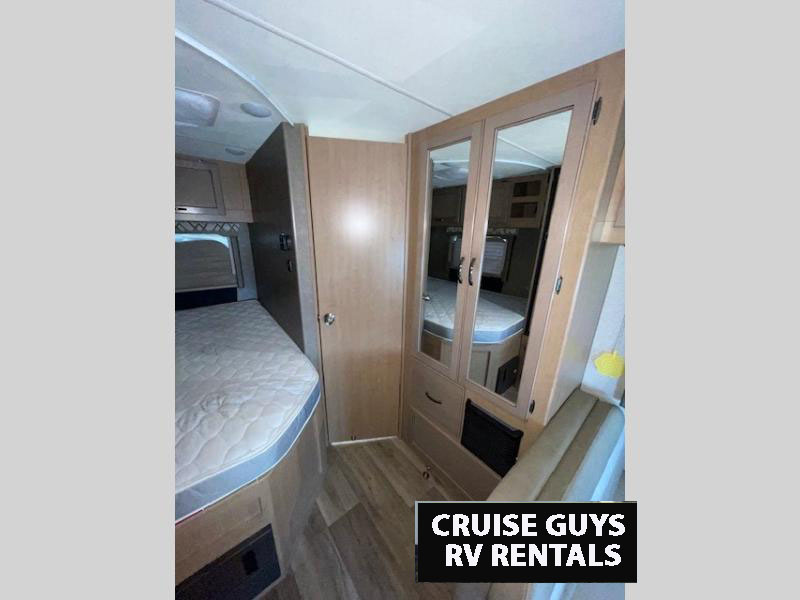 RV rental interior featuring a bed on the left and a mirrored wardrobe on the right for compact travel.. Thor Four Winds 2020