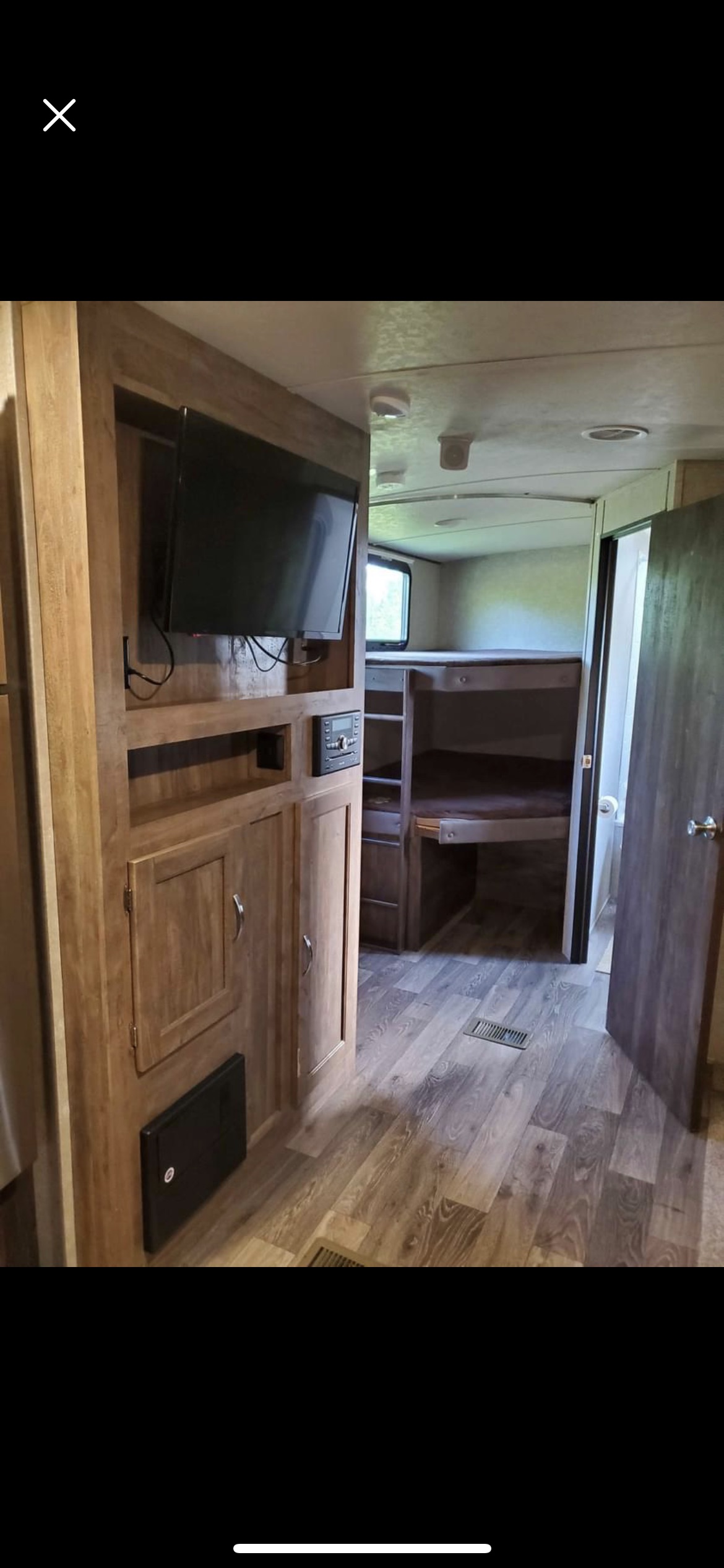 Inside an RV rental, featuring a built-in entertainment center with TV, and a rear bunk room with two beds.. Forest River Vibe 2017