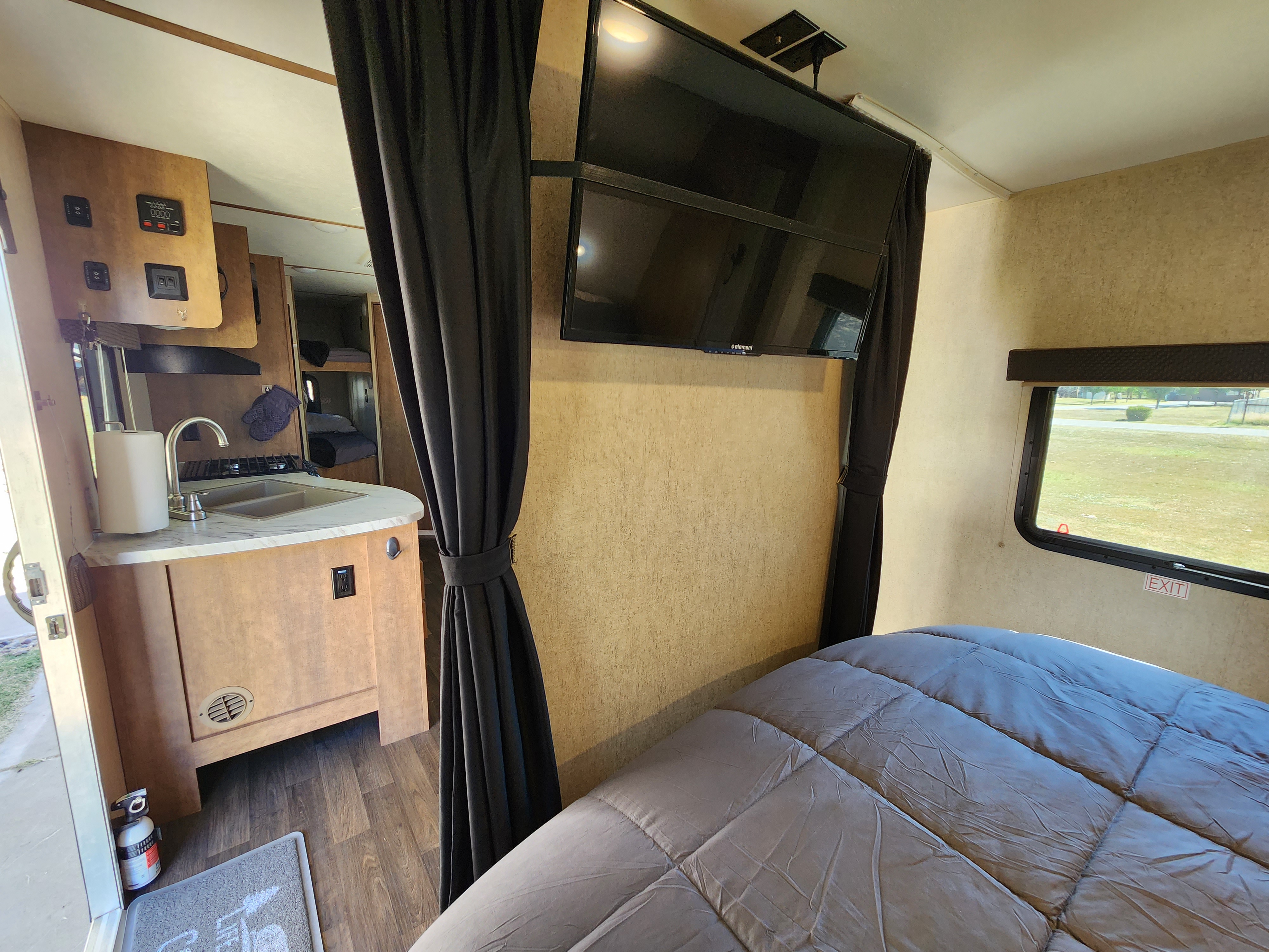 RV rental interior with kitchen sink, TV, and sleeping areas including a large bed and bunk beds.. Starcraft Launch Outfitter 2018