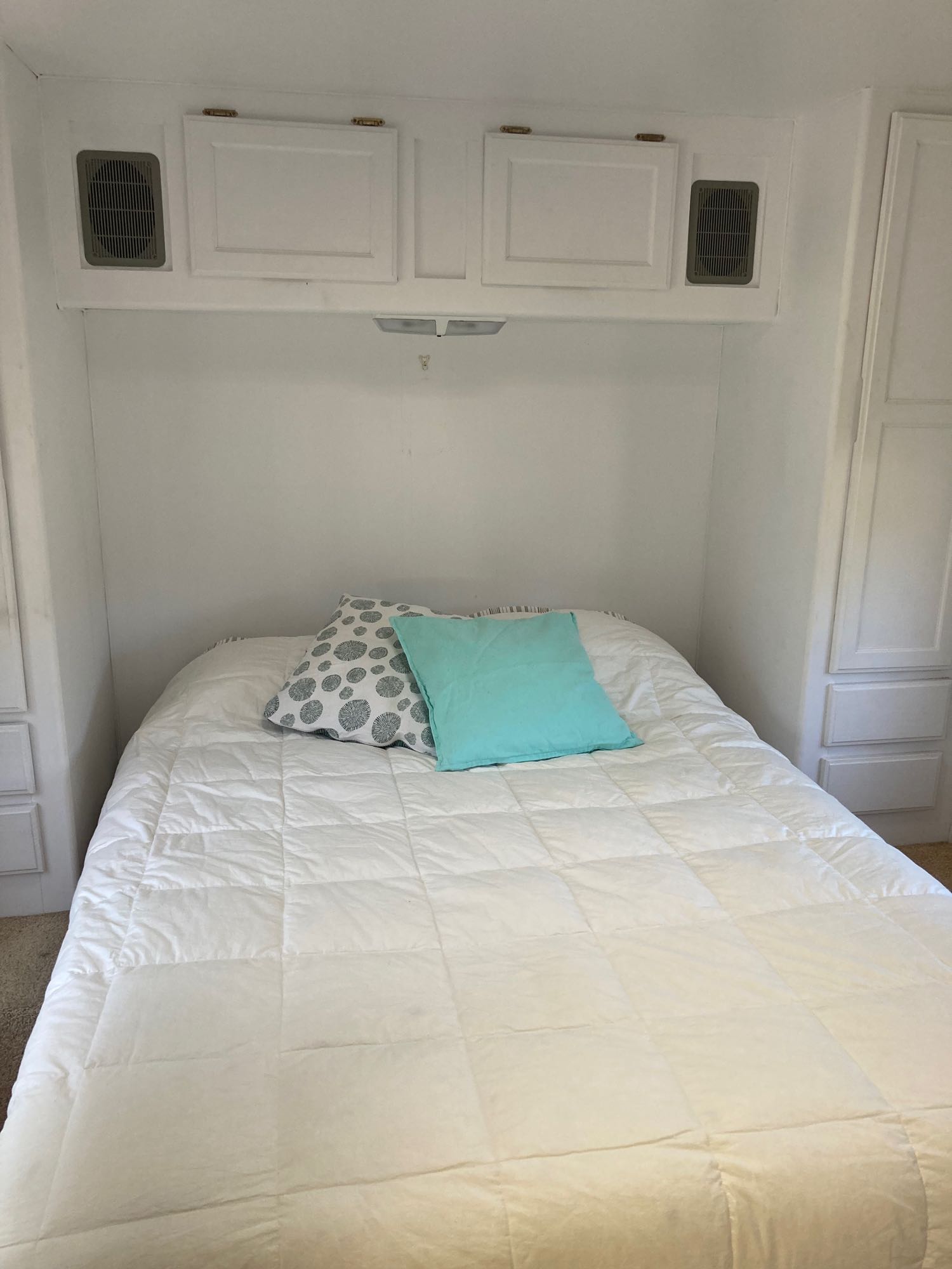 Inviting RV rental bedroom with a comfy white bed, accent pillows, and convenient overhead cabinets.. Gulf Stream Cavalier 2000