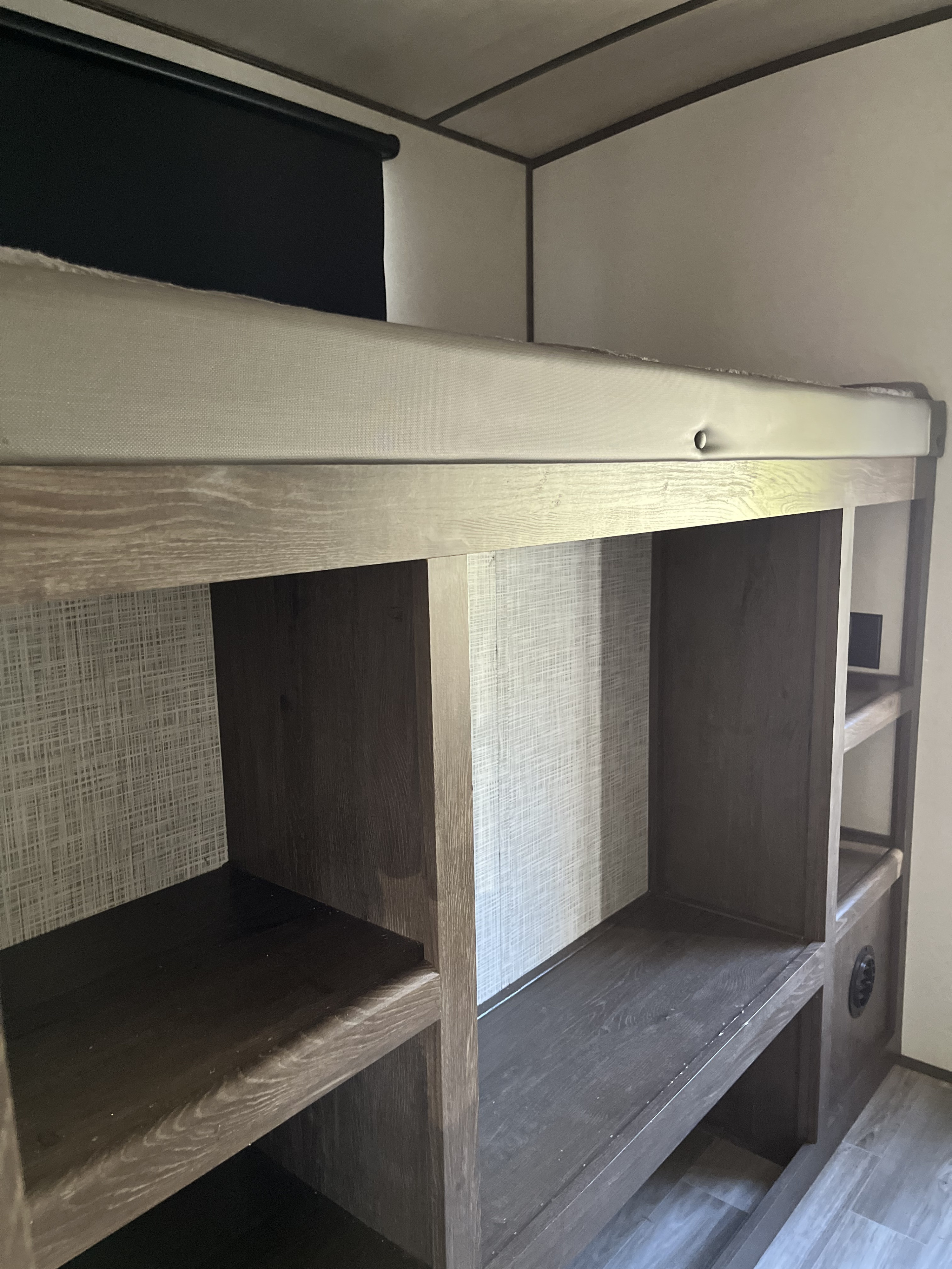 RV rental bunk area: Compact sleeping with wood-look shelving & cubbies, textured walls, privacy blind.. Forest River Wildwood Heritage Glen 2020