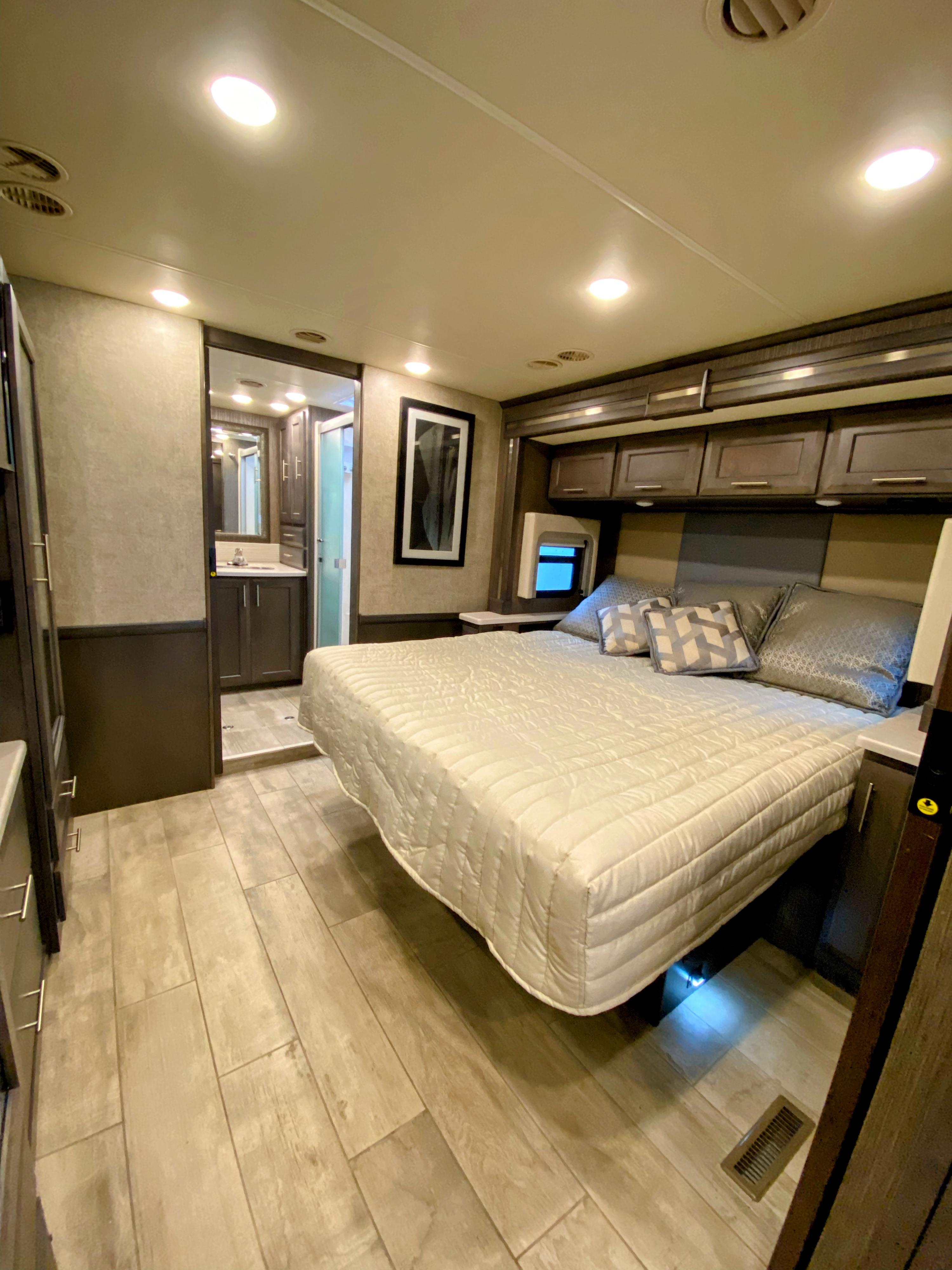 Spacious RV rental bedroom with a large bed, light flooring, and en-suite bathroom access, offering comfort on the go.. Thor Aria 2020