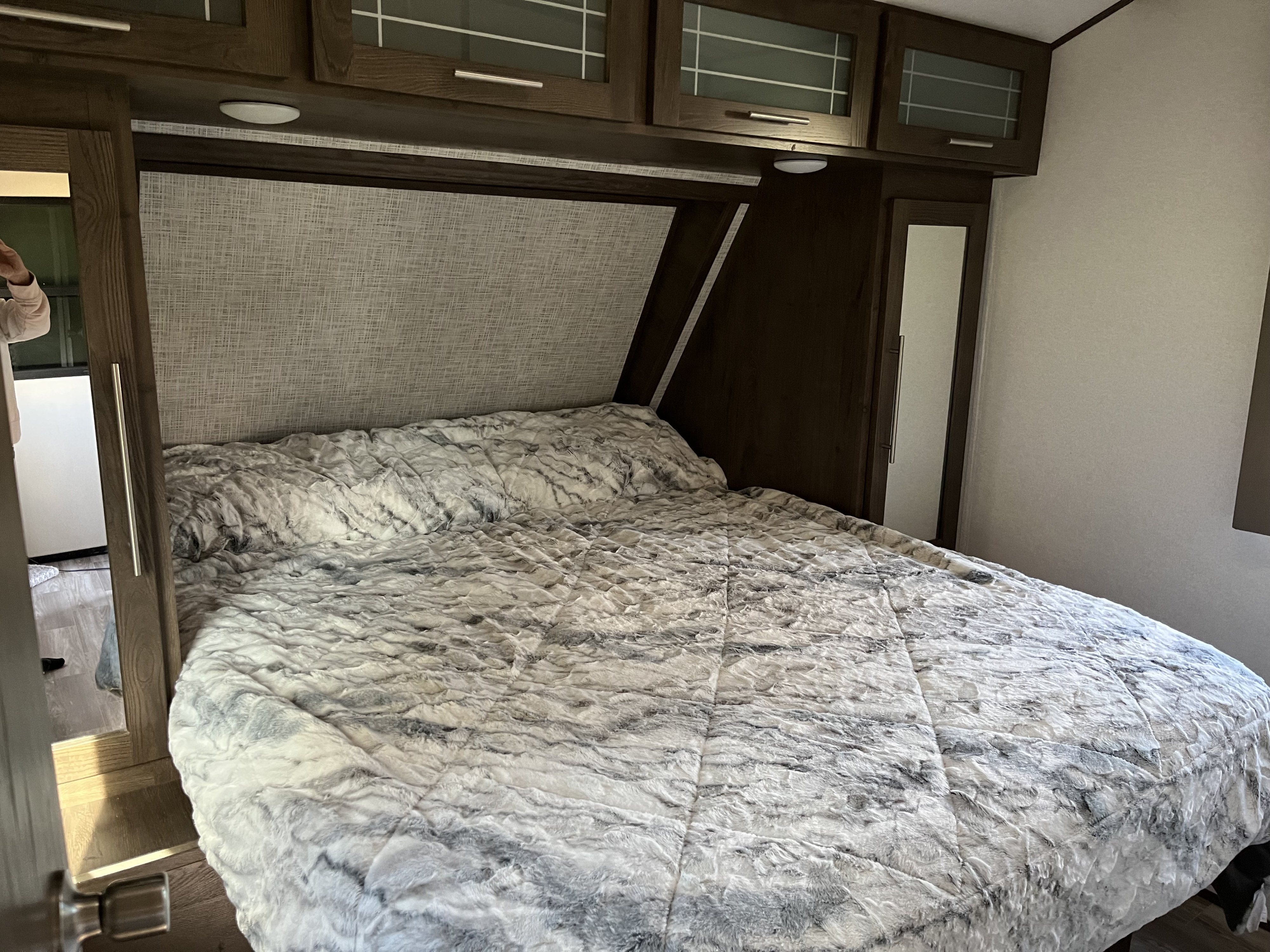 Comfortable RV rental bedroom featuring a soft bed, overhead cabinets, and built-in storage. Ideal for travel.. Forest River Wildwood Heritage Glen 2020