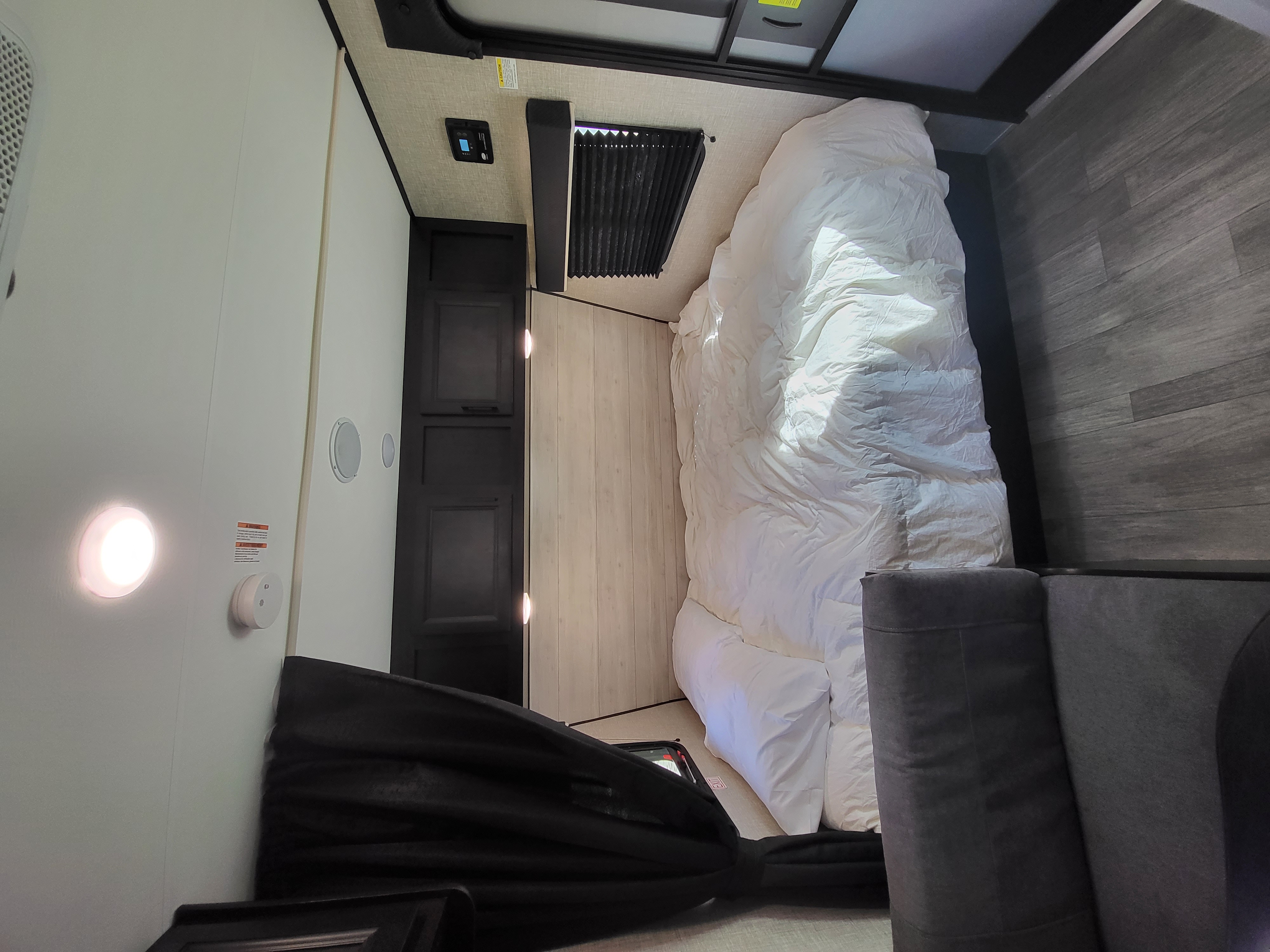 RV rental interior: comfortable bedroom with a spacious white bed, dark cabinets, and mixed flooring for a cozy travel space.. Jayco Jay Flight SLX 2022
