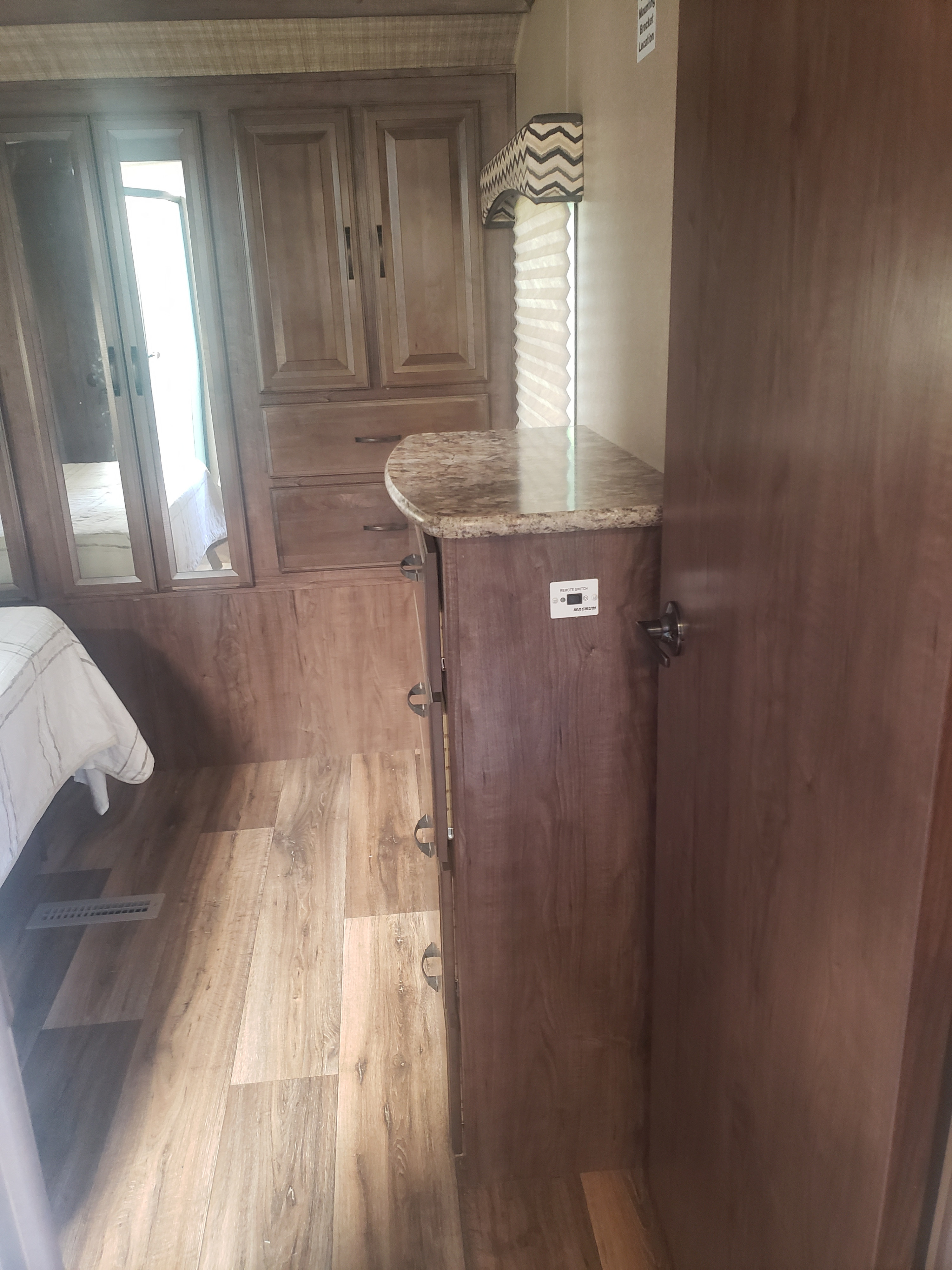 Explore this RV rental's bedroom interior, featuring stylish wood cabinets, a mirrored closet, and durable wood-look flooring.. Cruiser RV Radiance Touring 2016