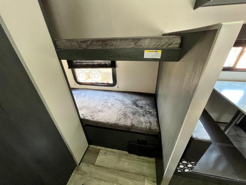 Explore this RV rental's interior: two stacked bunk beds, small window, and a glimpse of the dining space.. Aspen Trail LE 2022