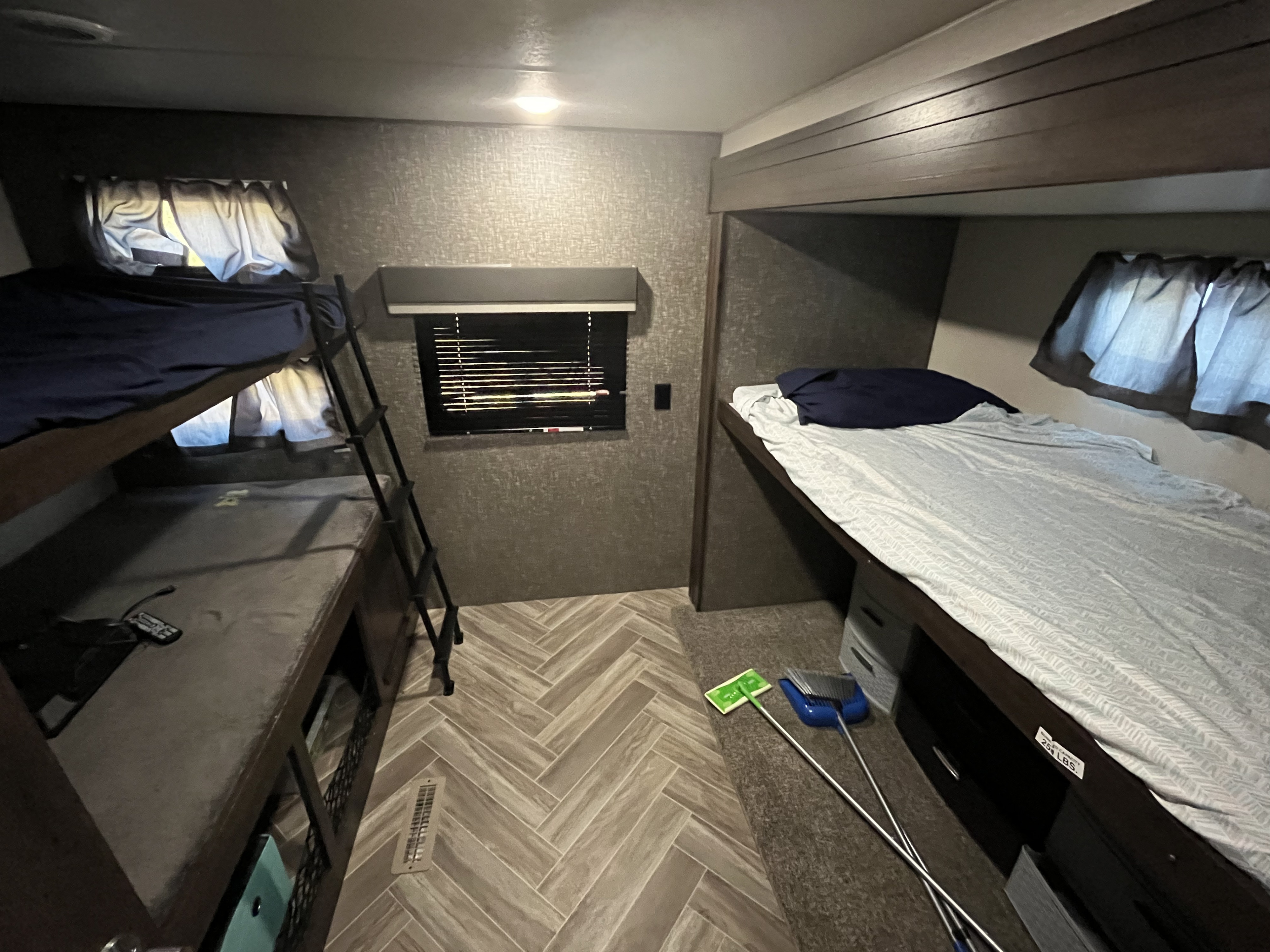 RV rental bunk bedroom: upper and lower bunks with ladder, window, and wood-look herringbone flooring.. K-Z Manufacturing Sportsmen 2021