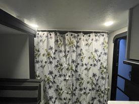 RV rental interior: A white floral shower curtain on a tension rod divides the living space. Recessed lights brighten this compact travel home.. Forest River Salem FSX 2022