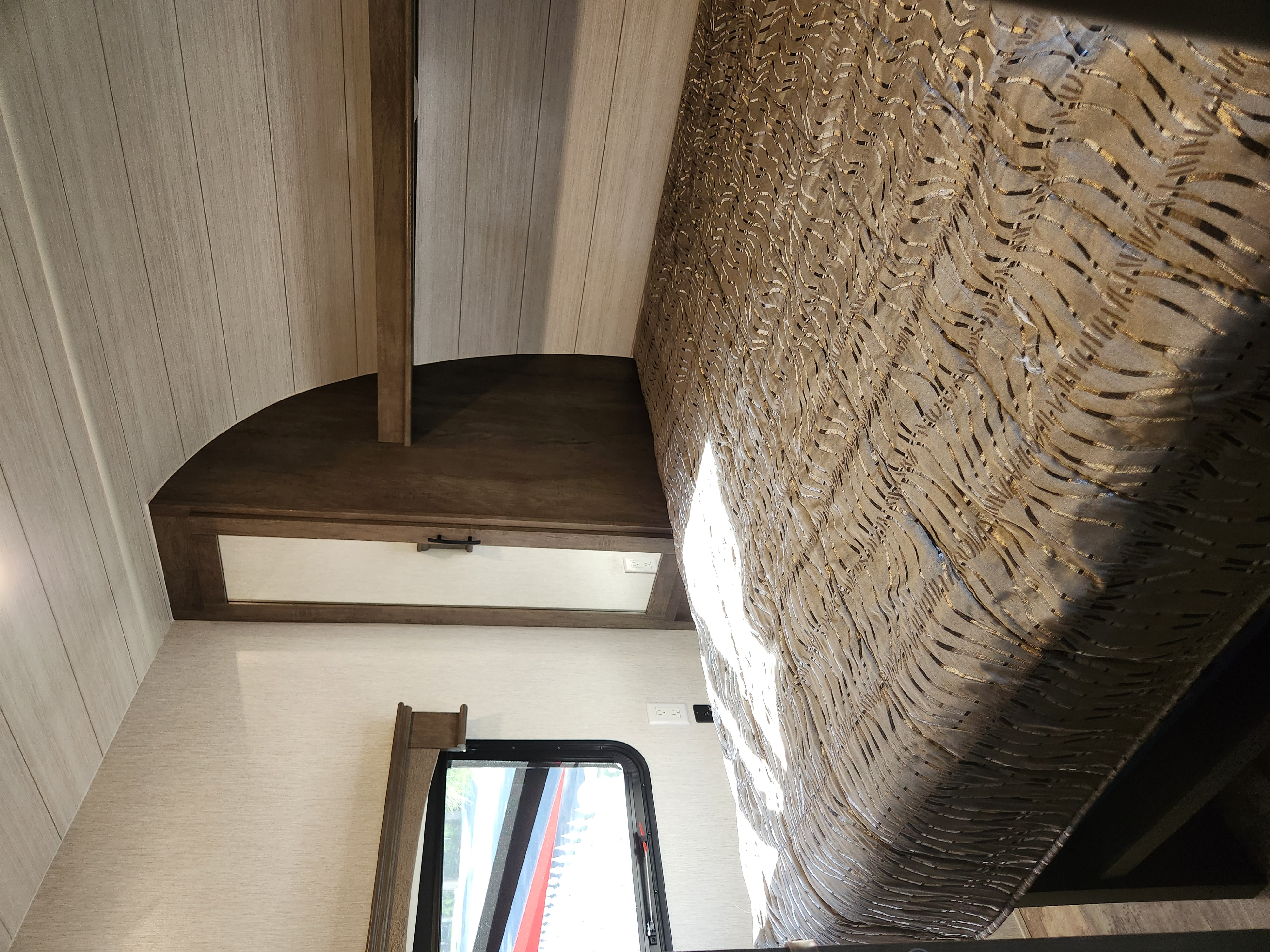 Cozy RV rental bedroom with a patterned bedspread, light wood paneling, and a convenient bedside shelf.. Forest River Shockwave 2022