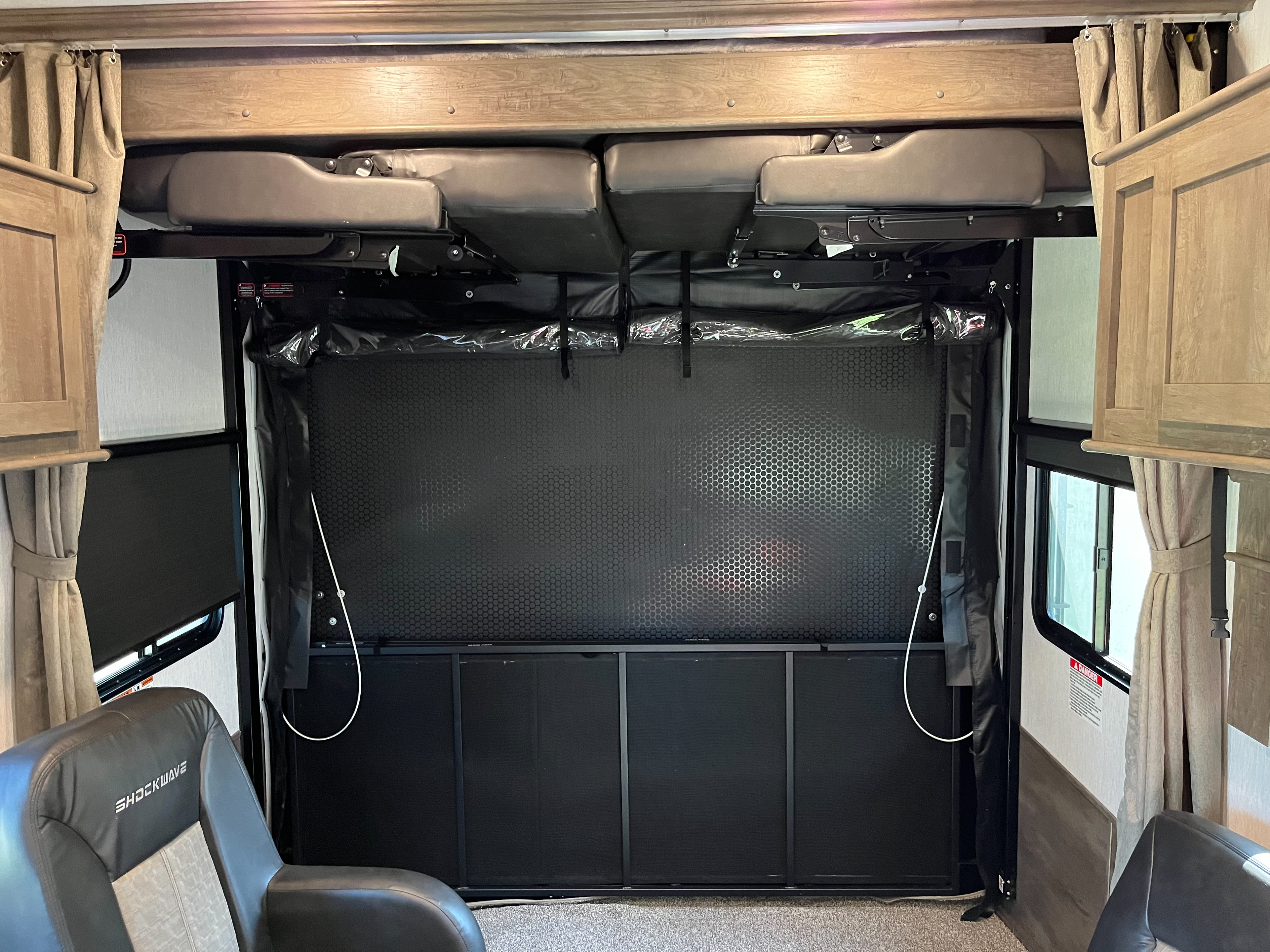 This RV rental toy hauler's rear interior features convertible sofa/beds raised above a lower cargo screen.. Forest River Shockwave 2022