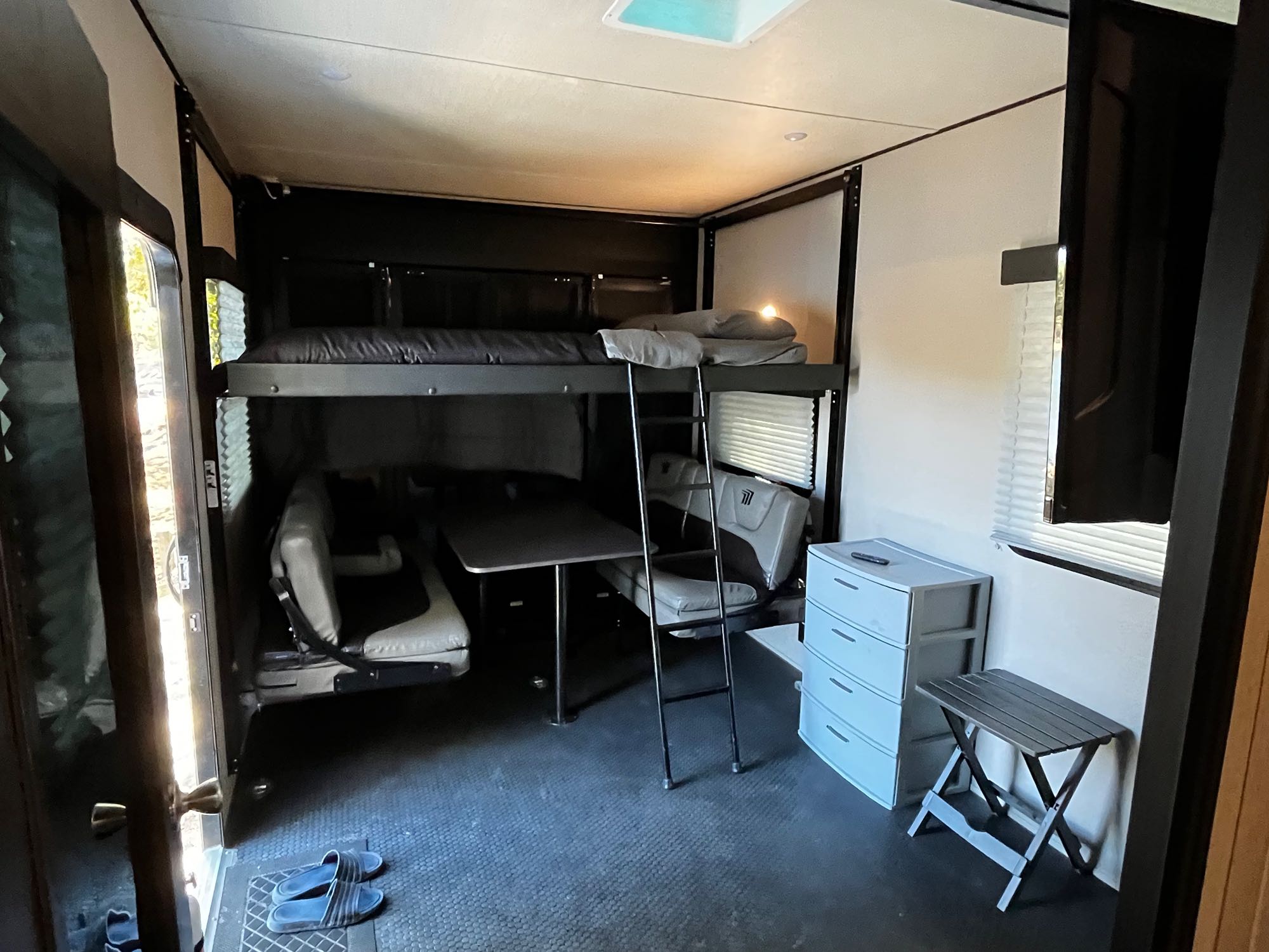 Rear bedroom arranged with a queen bed above 2 couches with dining table in the middle. . Grand Design Momentum 2021