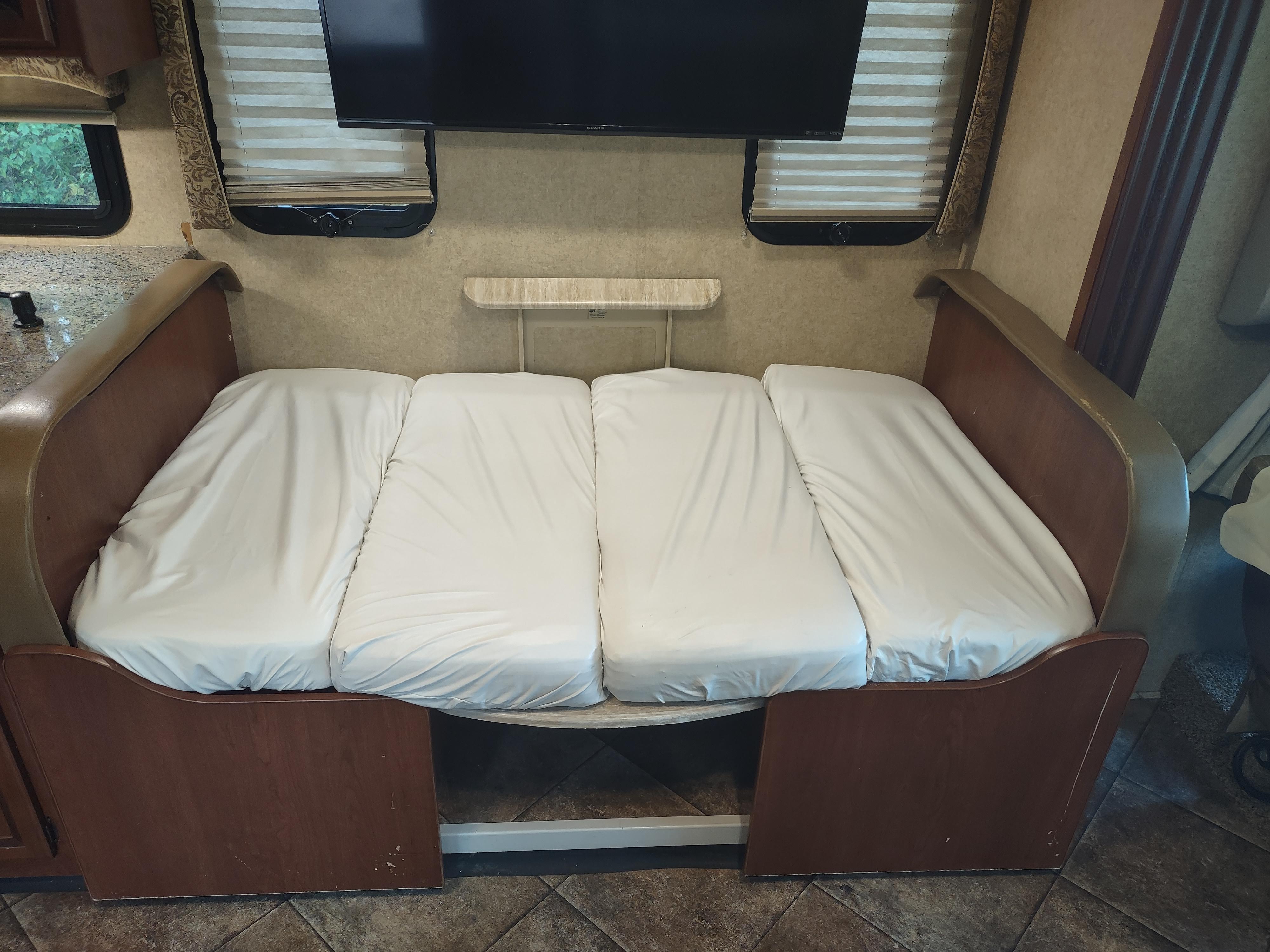 RV rental: RV's convertible sofa bed featuring three white cushions, integrated into a compact interior.. Thor Windsport 2015