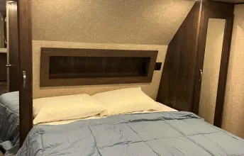 This cozy RV rental bedroom offers a comfortable bed, built-in shelf, and mirrored closet for your travels.. Forest River Vibe 2018