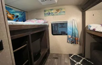 This cozy RV rental bunkhouse interior features multiple bunk beds and a TV, ideal for family camper travel.. Forest River Vibe 2018