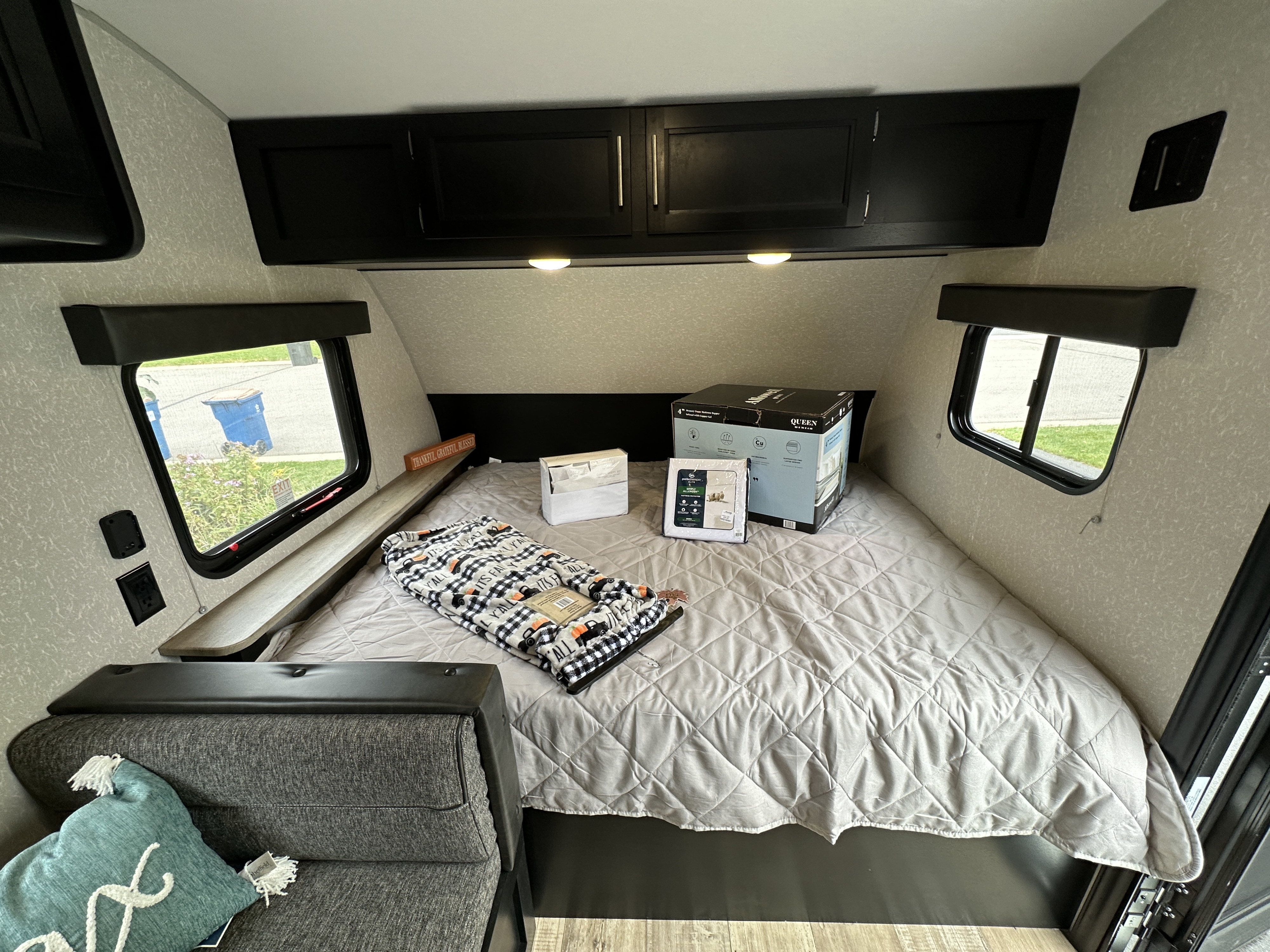RV rental bedroom features a cozy queen bed setup with new mattress topper, overhead storage, and windows.. Forest River Cherokee Wolf Pup 2022