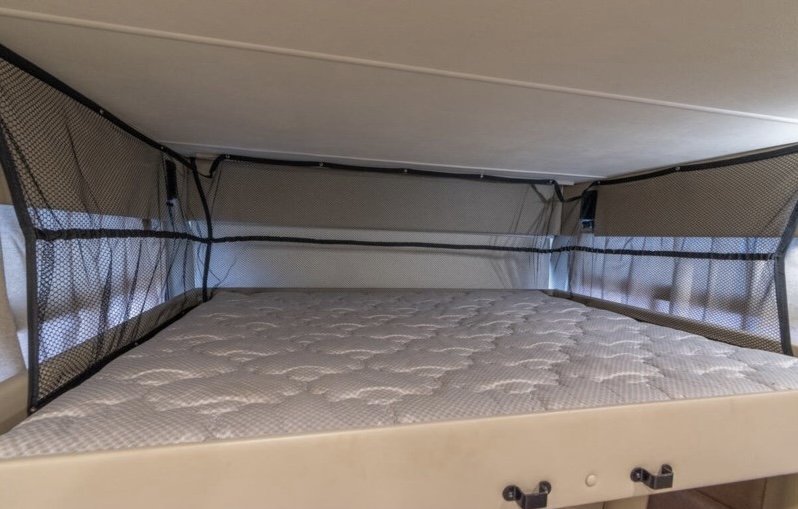 Comfortable RV rental bunk bed with mesh safety netting, ensuring a secure and cozy sleep in your home on wheels.. Thor Hurricane 2017