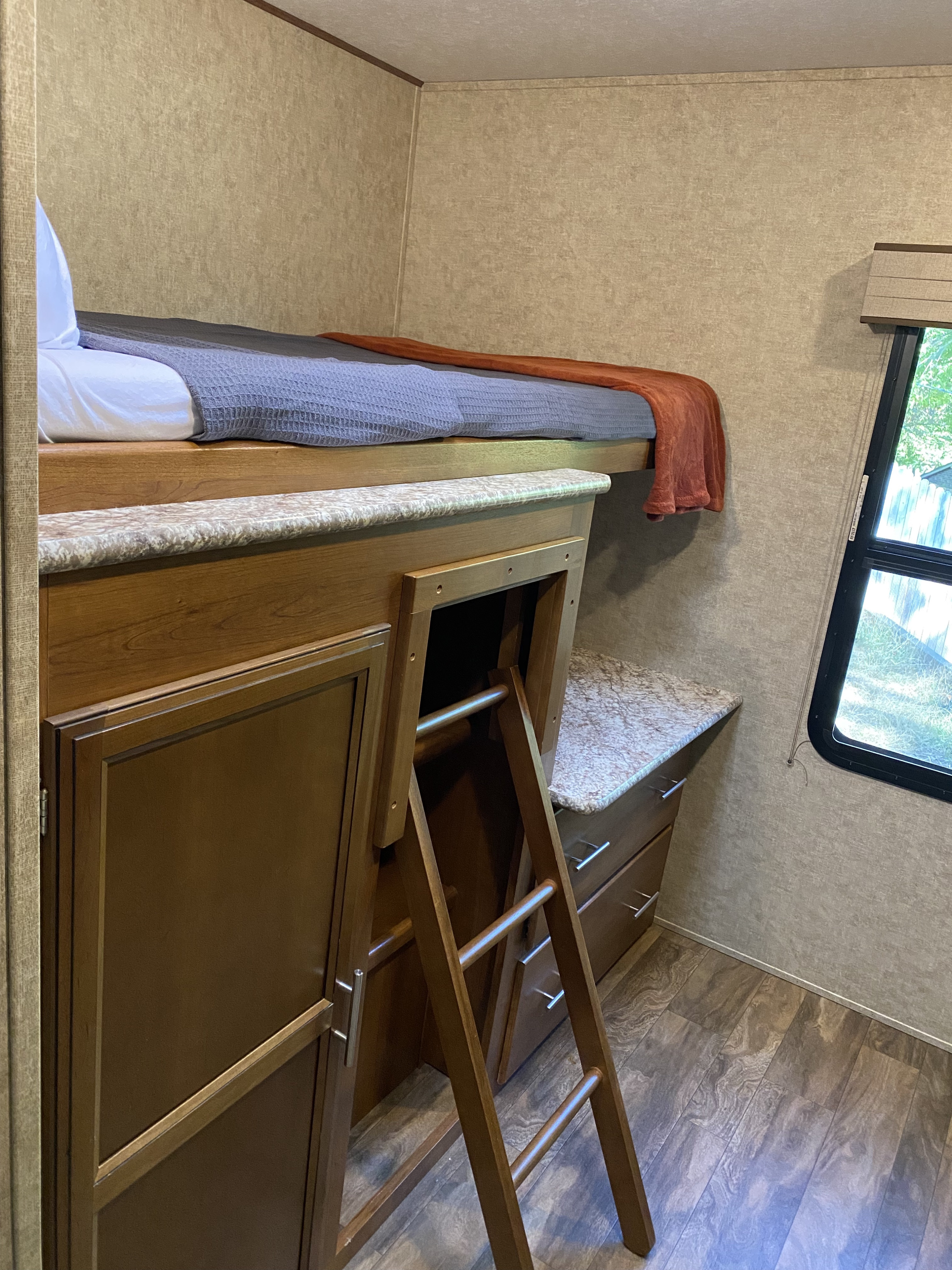 Compact RV rental interior: bunk bed with bedding, access ladder, and under-bunk storage cabinet.. Other Other 2017