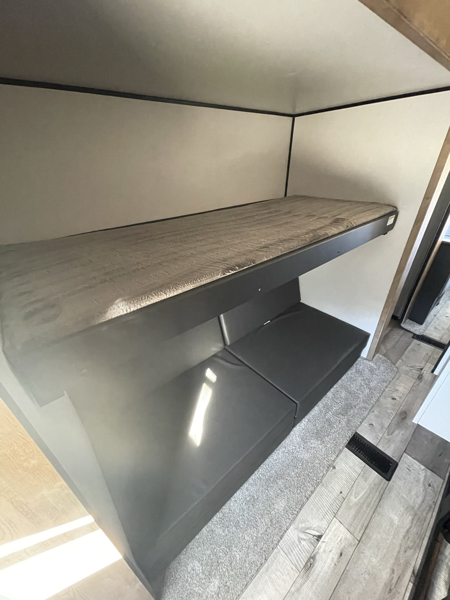 Inside your RV rental: a cozy bunk bed setup with upper mattress and convertible lower seating. Perfect for restful nights.. Keystone RV Springdale 2022