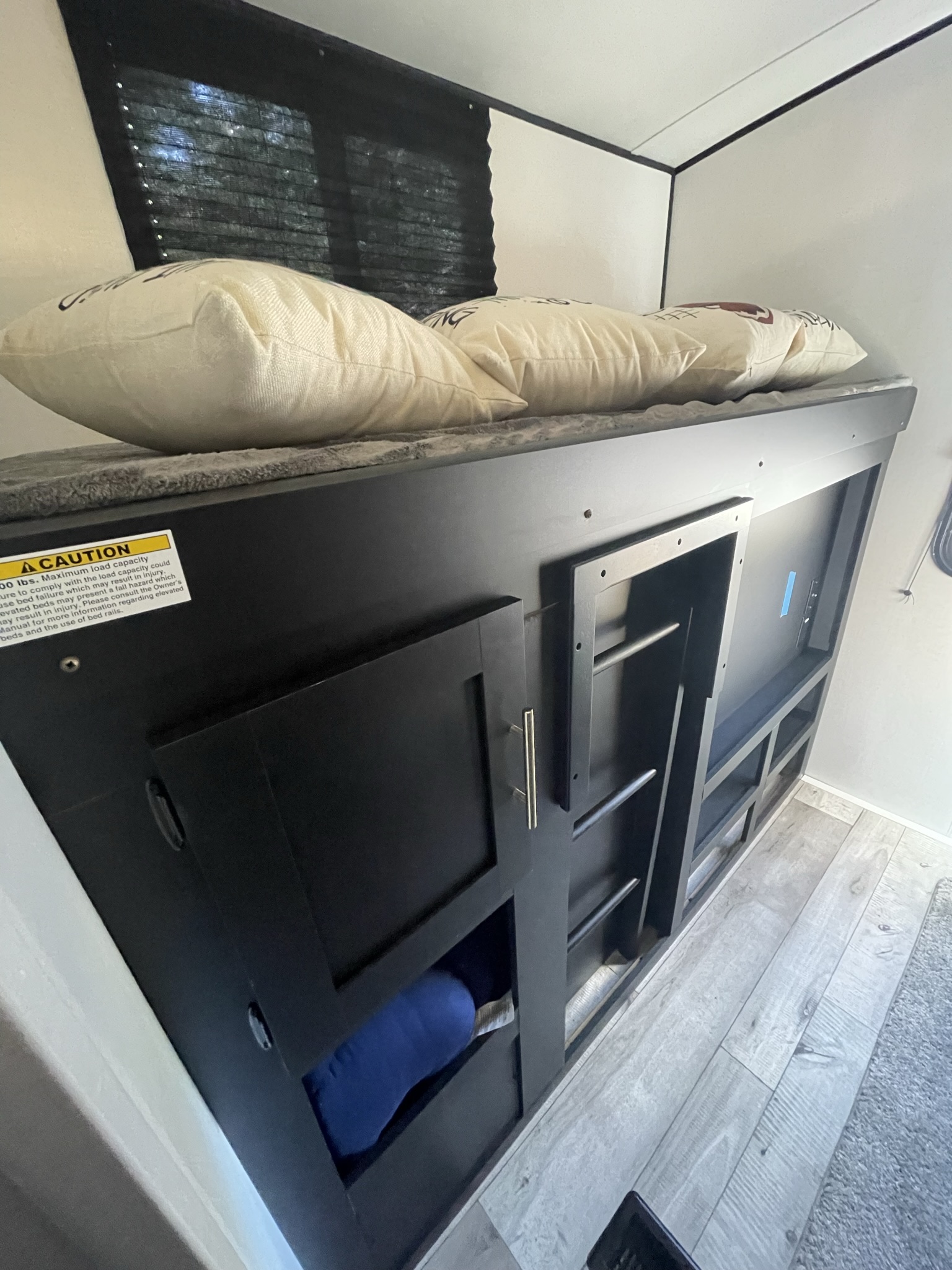 RV rental interior: a sturdy bunk bed with a weight caution label, integrated storage cubbies, and shelving below.. Keystone RV Springdale 2022